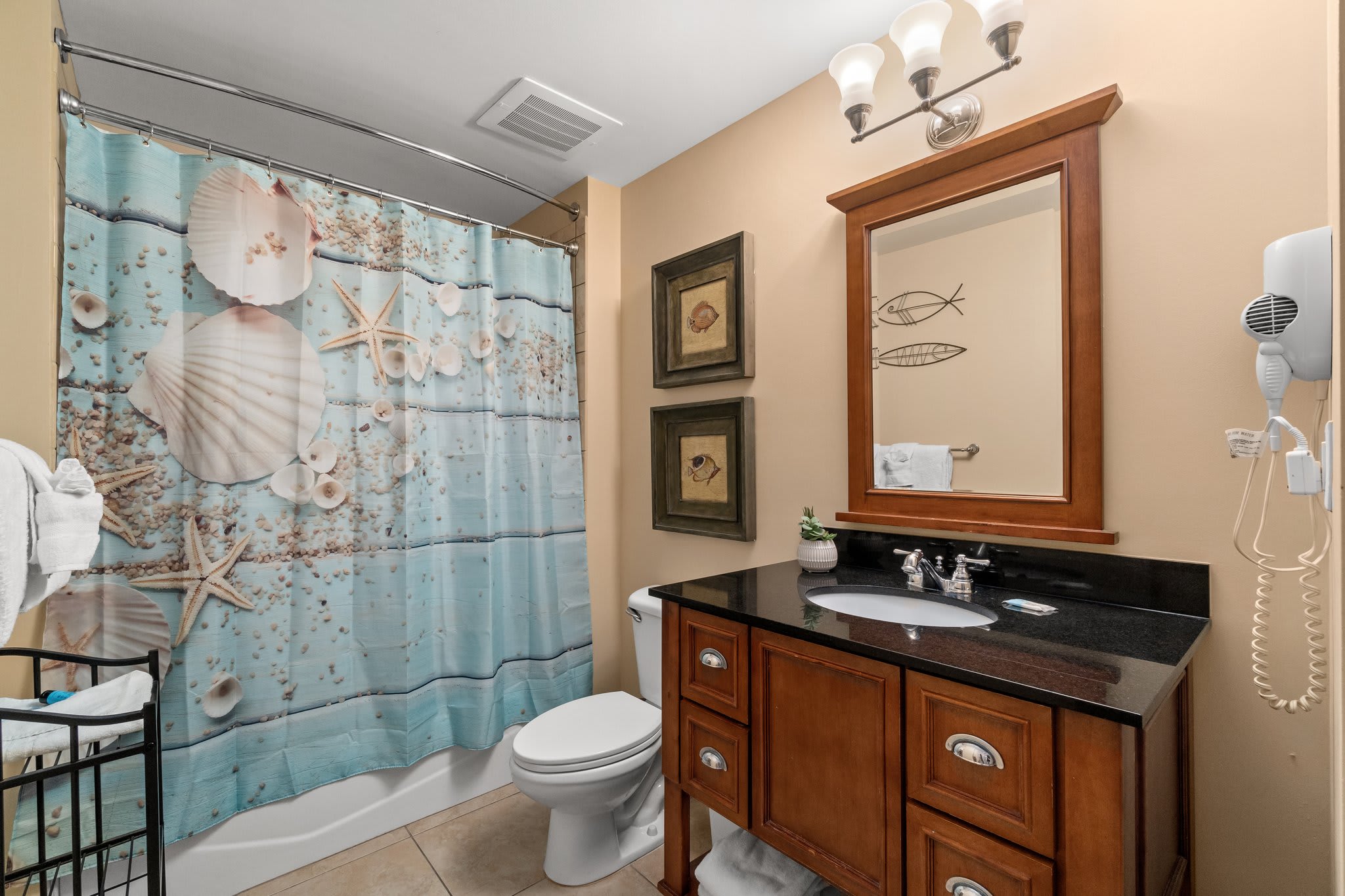Another bathroom with vanity, hair dryer, and bath tub.