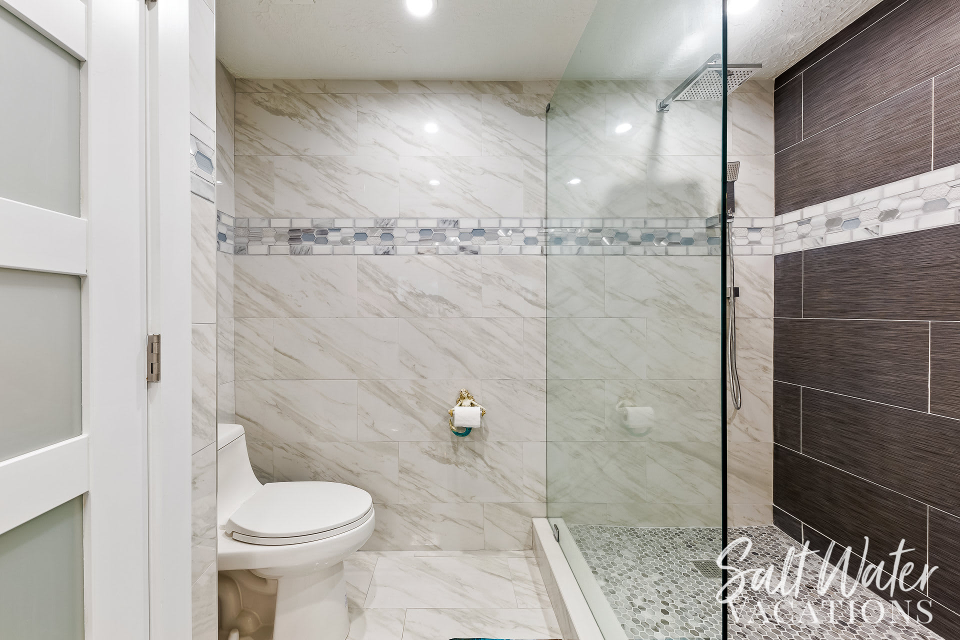 Walk in master bathroom with custom tile and LED water sensors 