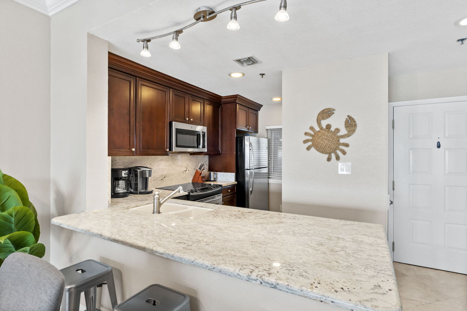 View into the fully stocked kitchen with all stainless steele appliances, cookware, drinkware, dinner ware, coffee pot, toaster. Full size refrigerator.
