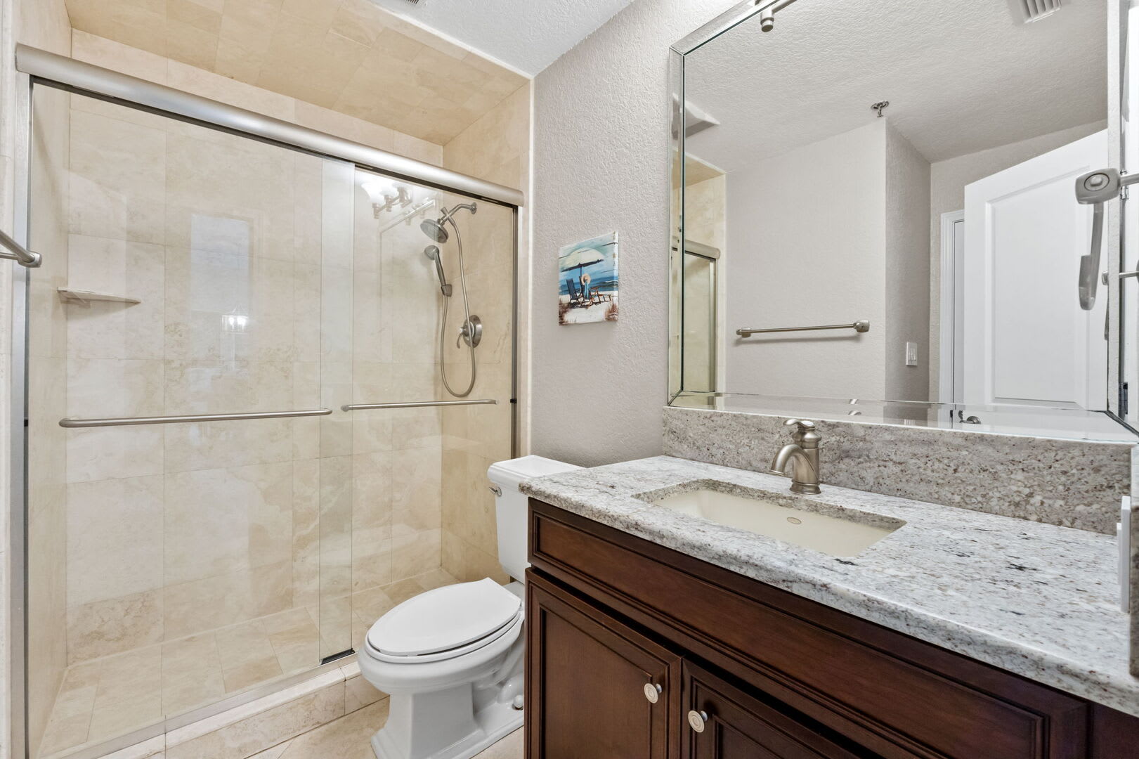 Guest bath offers oversized step-in shower, single vanity, mirror and toilet .