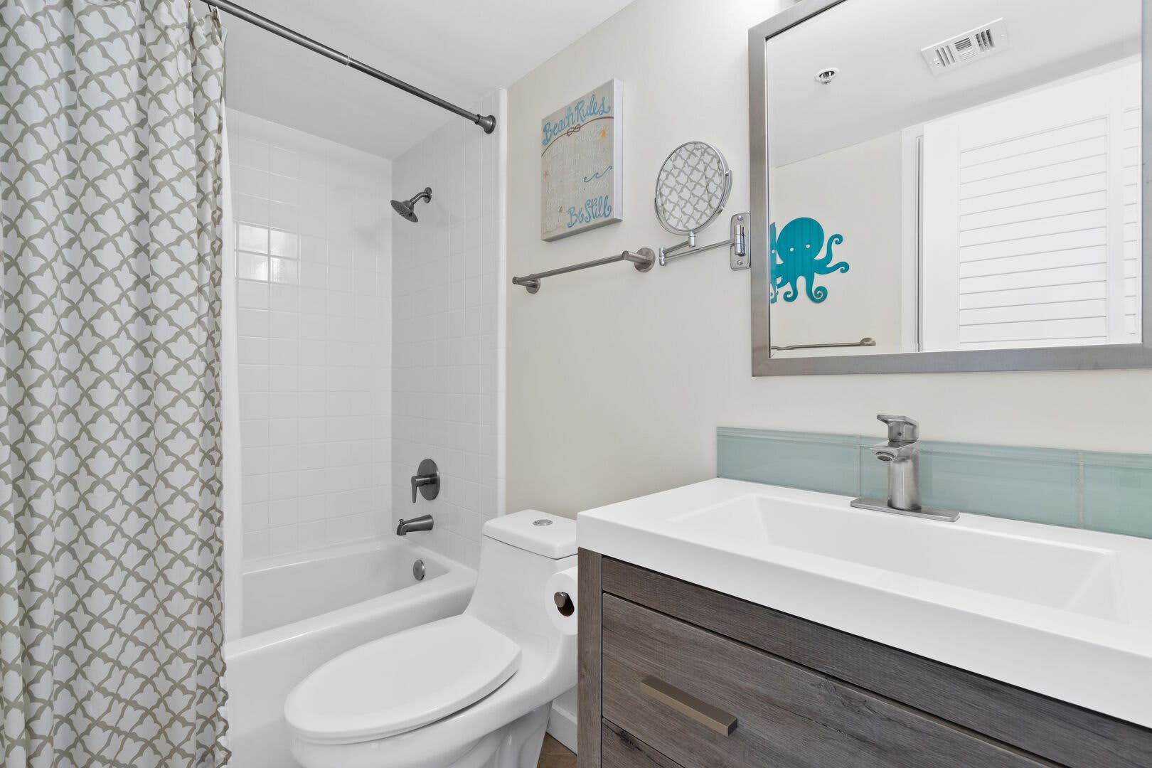 The guest bath is a shared bath for the two guest bedrooms. Offering a large vanity, wall mirror, bath/tub combo.