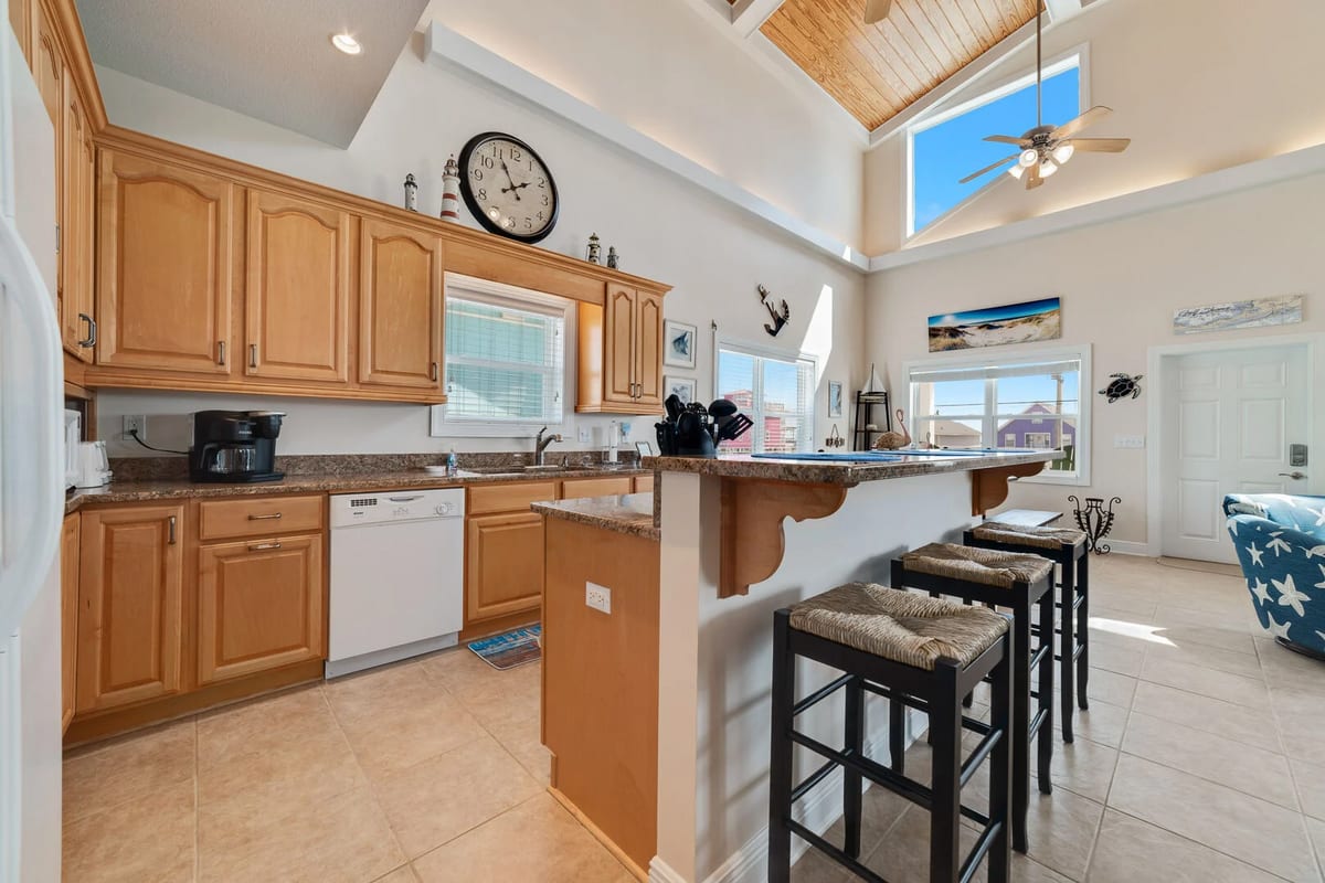 The classic, fully equipped kitchen boasts high-quality appliances, sleek countertops, and a breakfast bar with seating for three.