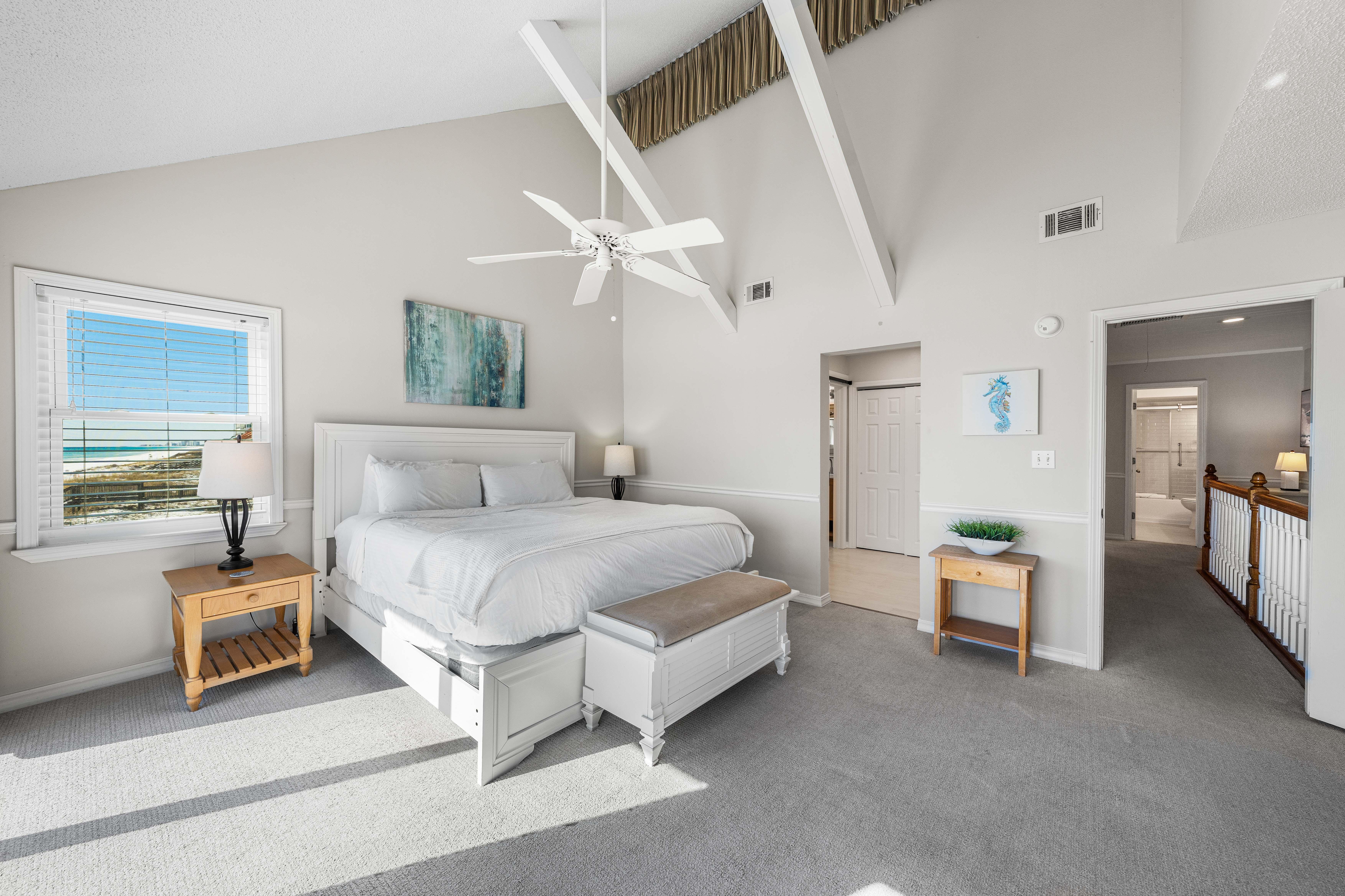 Lofted ceiling with white beams give this primary king bedroom a light and airy feel.