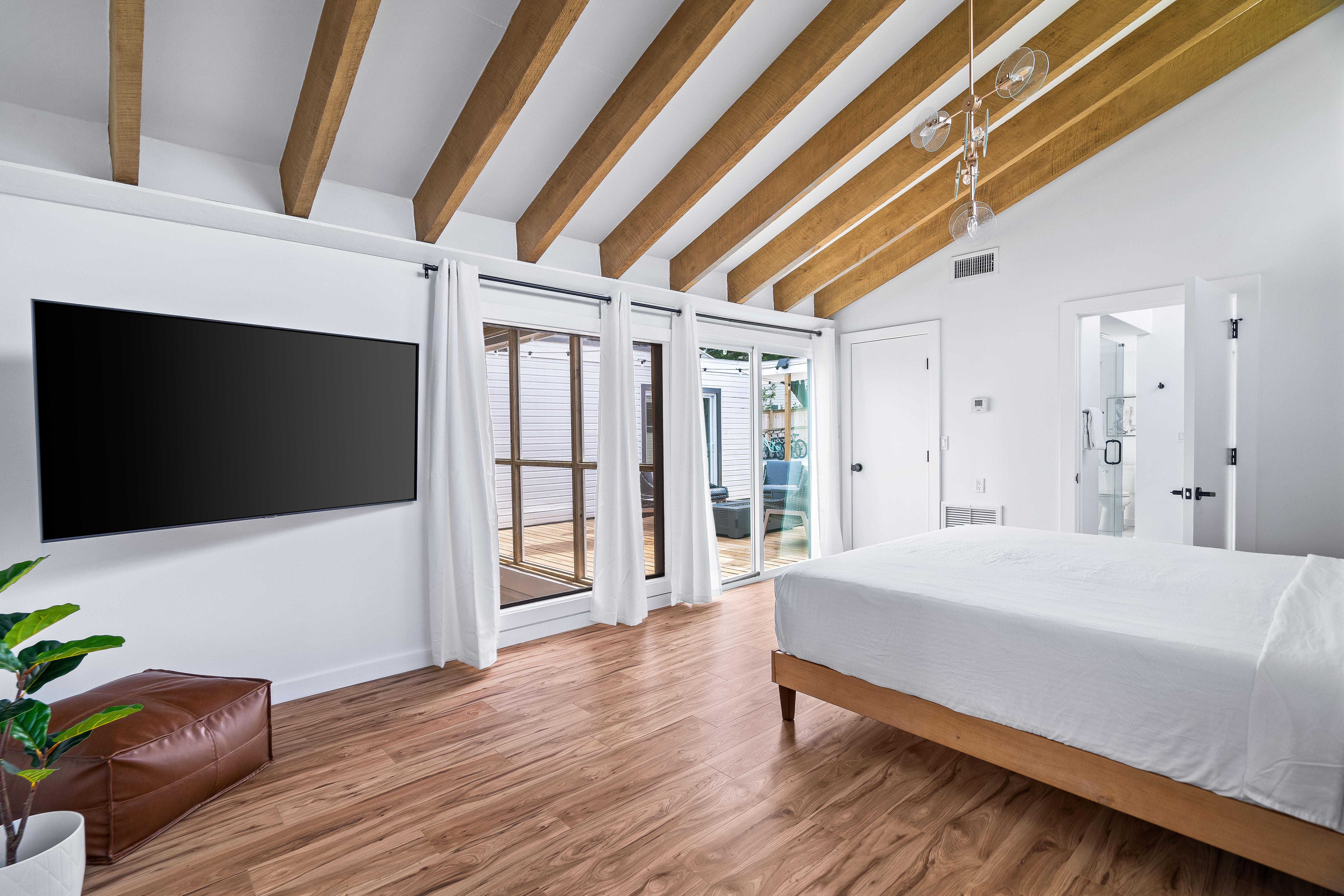 King bed primary bedroom with large flat screen tv and sliding door opening to the pool deck area. Bedroom #1