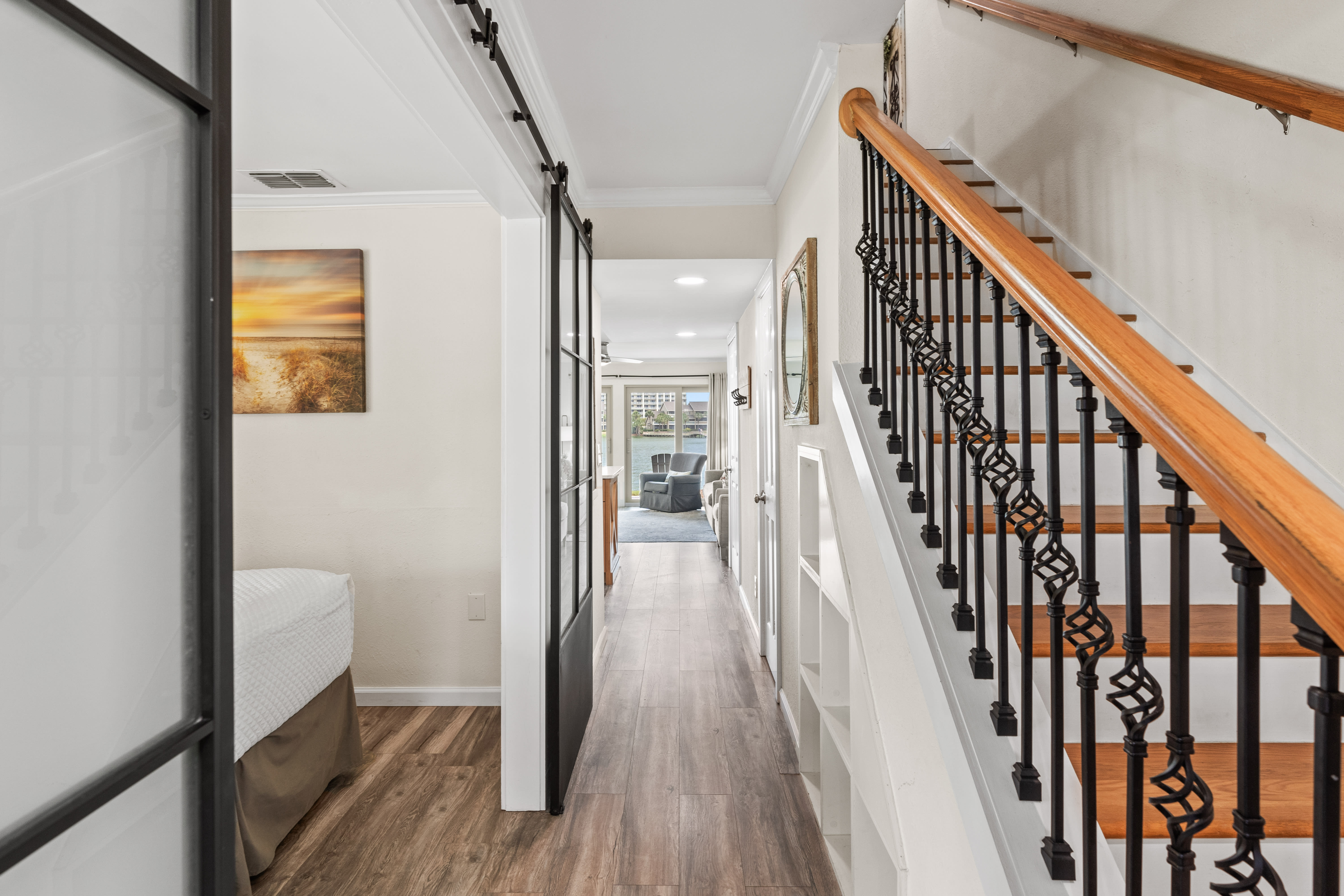 Step into your elegant hallway where warm wood floors guide you past stylish artwork toward inviting living spaces upstairs.