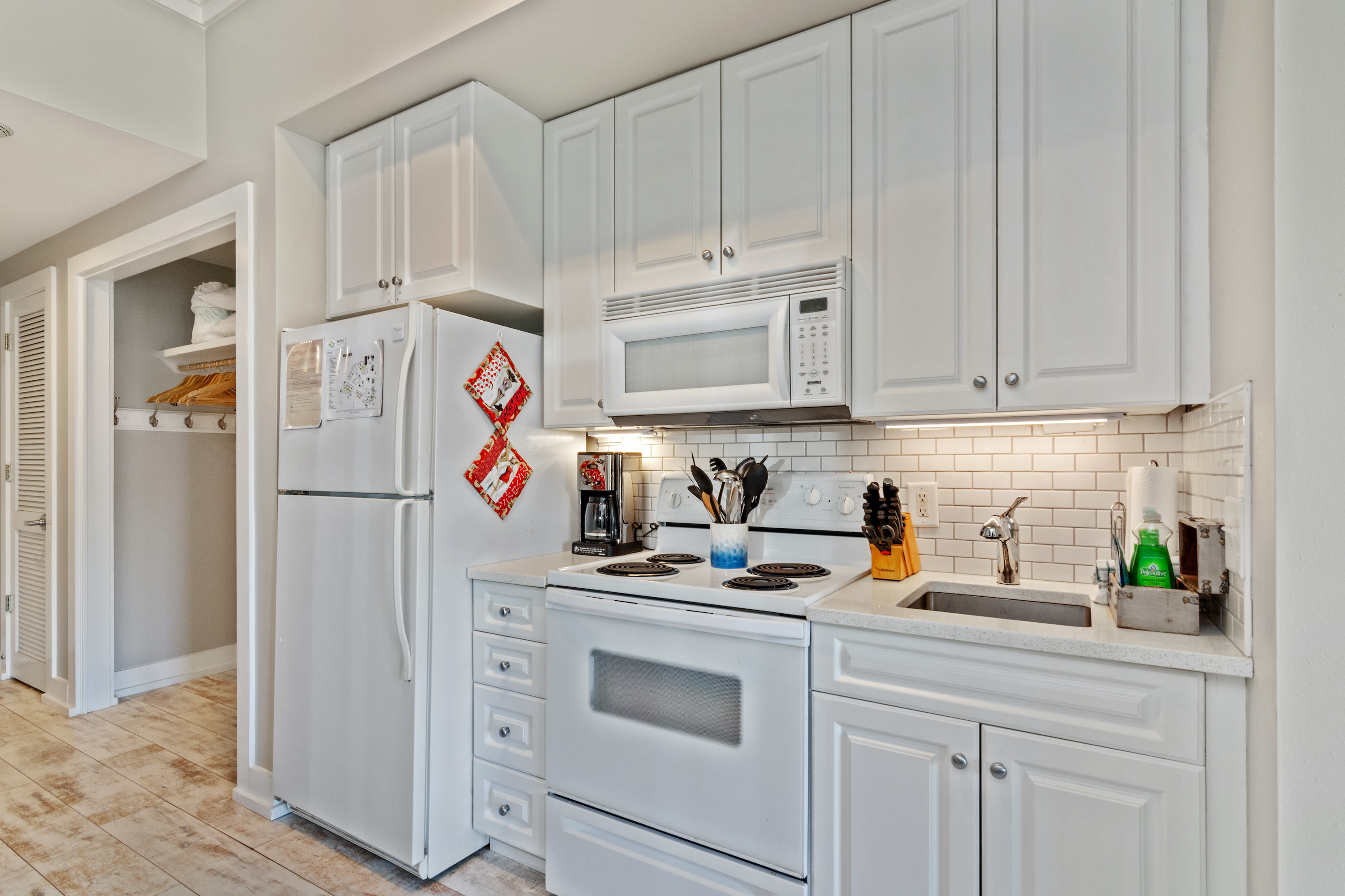 Fully equipped kitchen with crisp white cabinetry, modern appliances, and a sleek subway tile backsplash—ideal for whipping up meals during your 30A stay.