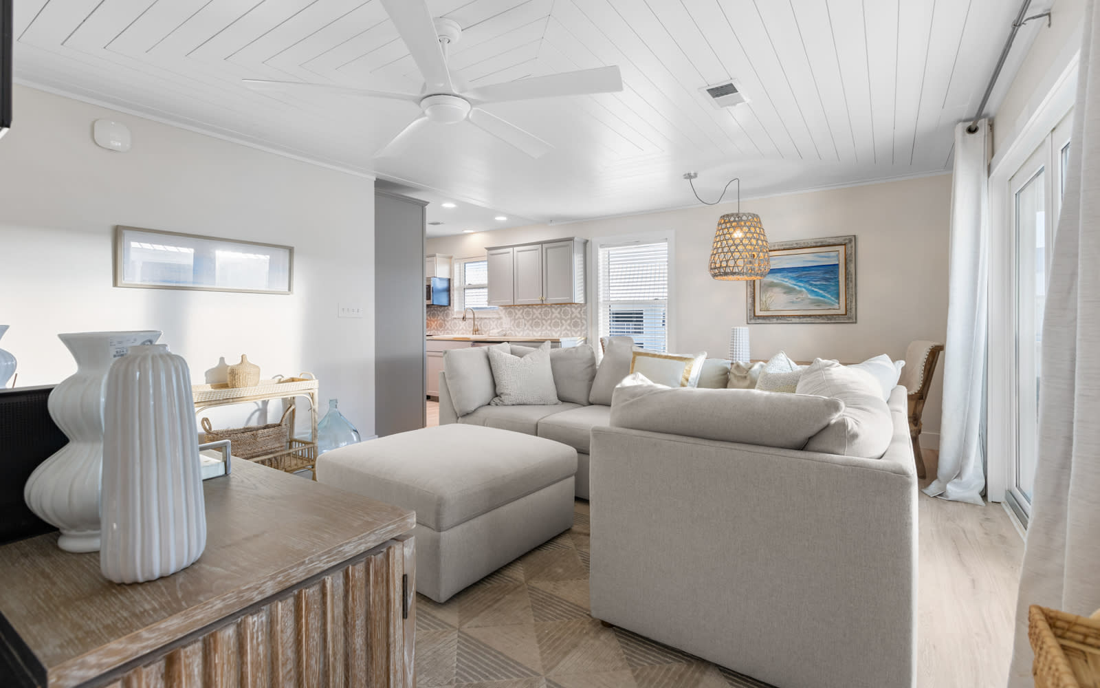 Relax in your airy coastal living room with plush sectional seating and modern kitchen beyond.