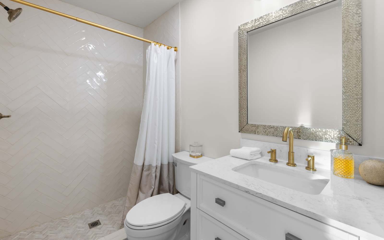 Unwind in your elegant bathroom featuring marble countertops, gold fixtures, and a refreshing shower with crisp white linens.