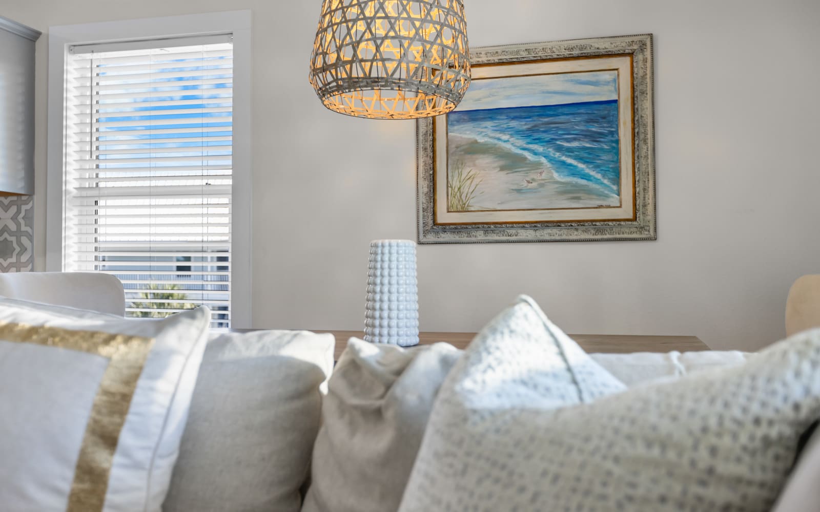 Sink into plush cushions beneath coastal artwork while natural light filters through your private blinds.