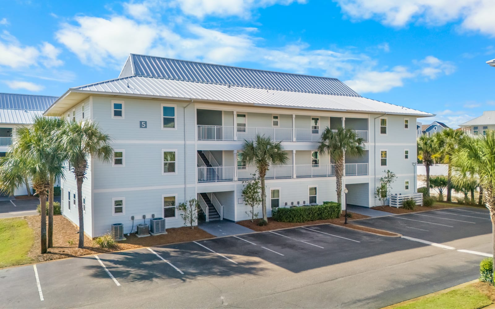 Modern coastal building with palm trees and convenient parking in a peaceful residential setting.