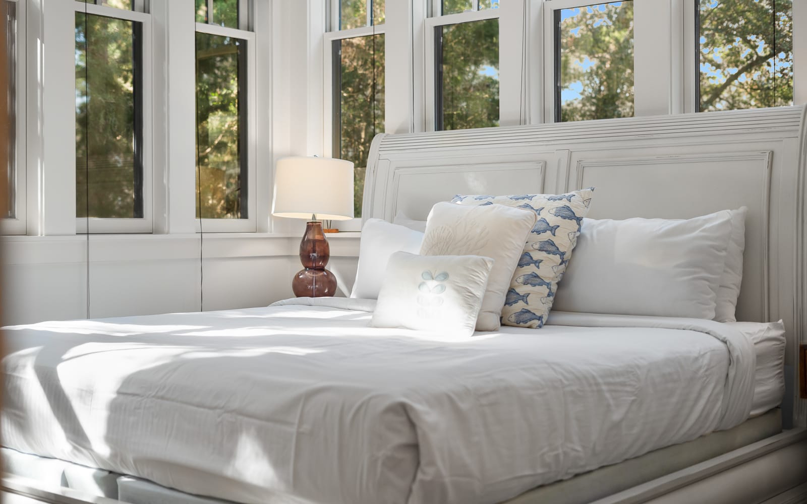 Wake up to sunlight streaming through expansive windows, creating your perfect morning sanctuary with crisp linens and peaceful tree views.