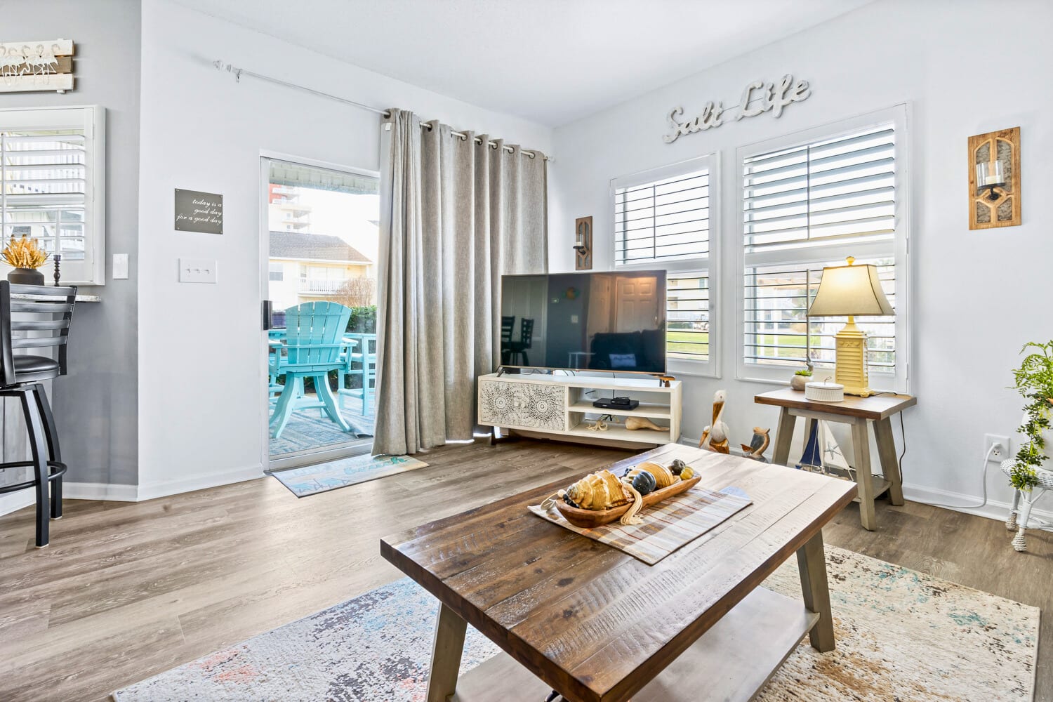 Relax in your bright living space with coastal touches, where morning light filters through plantation shutters and opens to your private patio retreat.