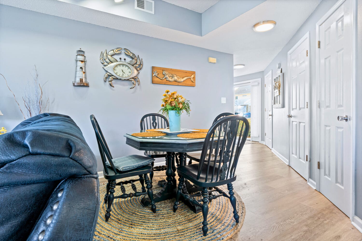 Gather around this charming dining table adorned with coastal touches, where you'll share meals surrounded by nautical art and warm lighting.