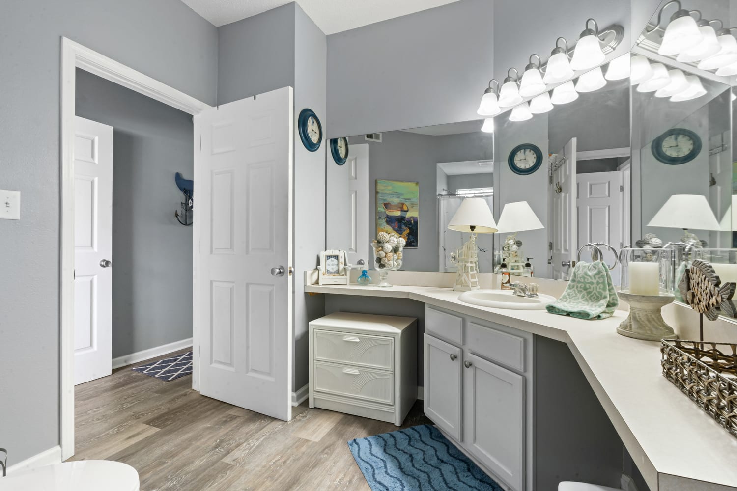Step into your spacious bathroom featuring elegant gray cabinetry, granite countertops, and coastal-themed touches that create a serene coastal retreat atmosphere.