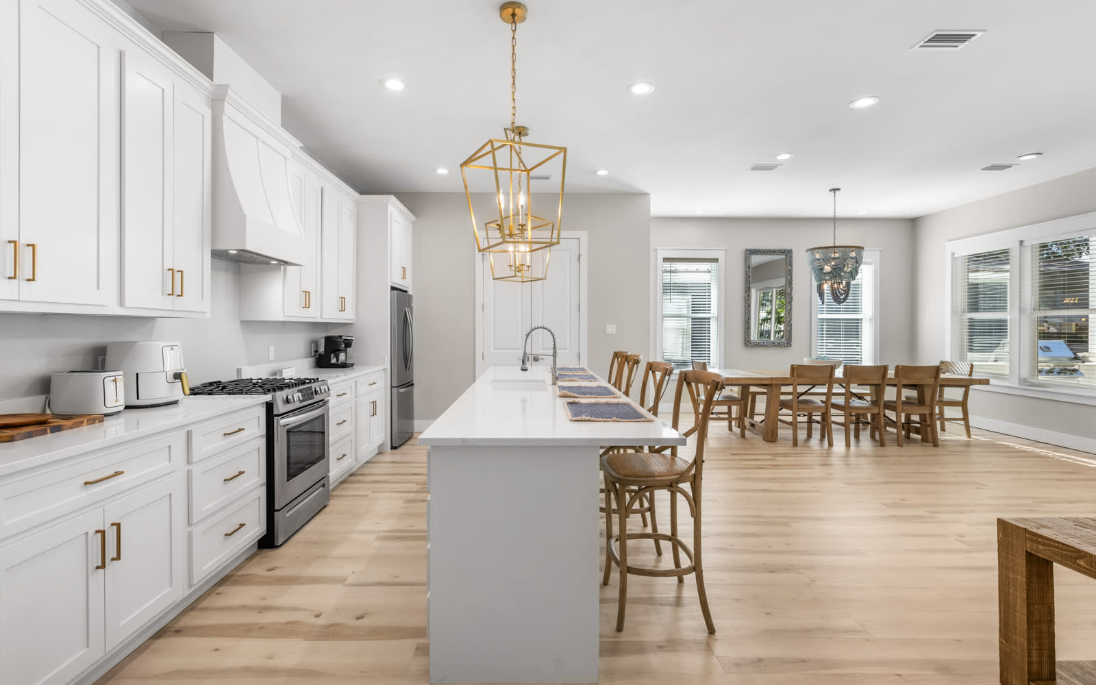Your spacious open kitchen flows seamlessly into the dining area, where golden pendant lights illuminate meals shared around the expansive island.