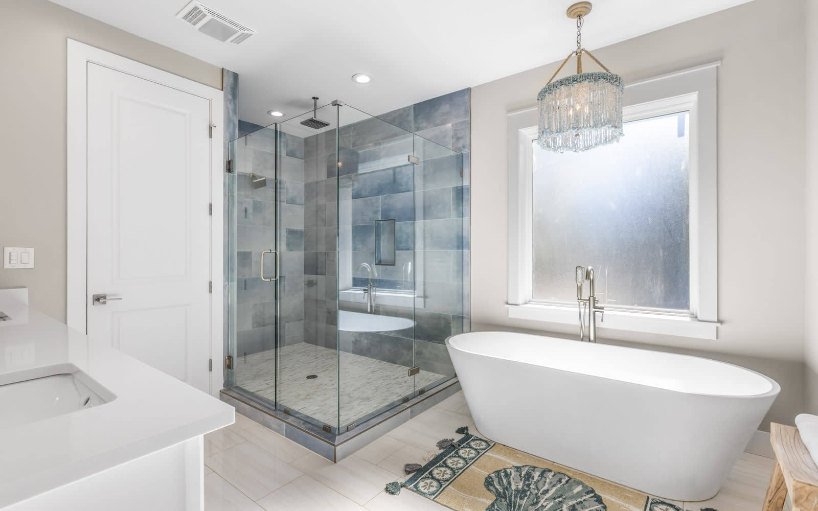 Unwind in your spa-like bathroom with a luxurious soaking tub and rainfall shower, where elegant crystal lighting creates the perfect ambiance for relaxation.