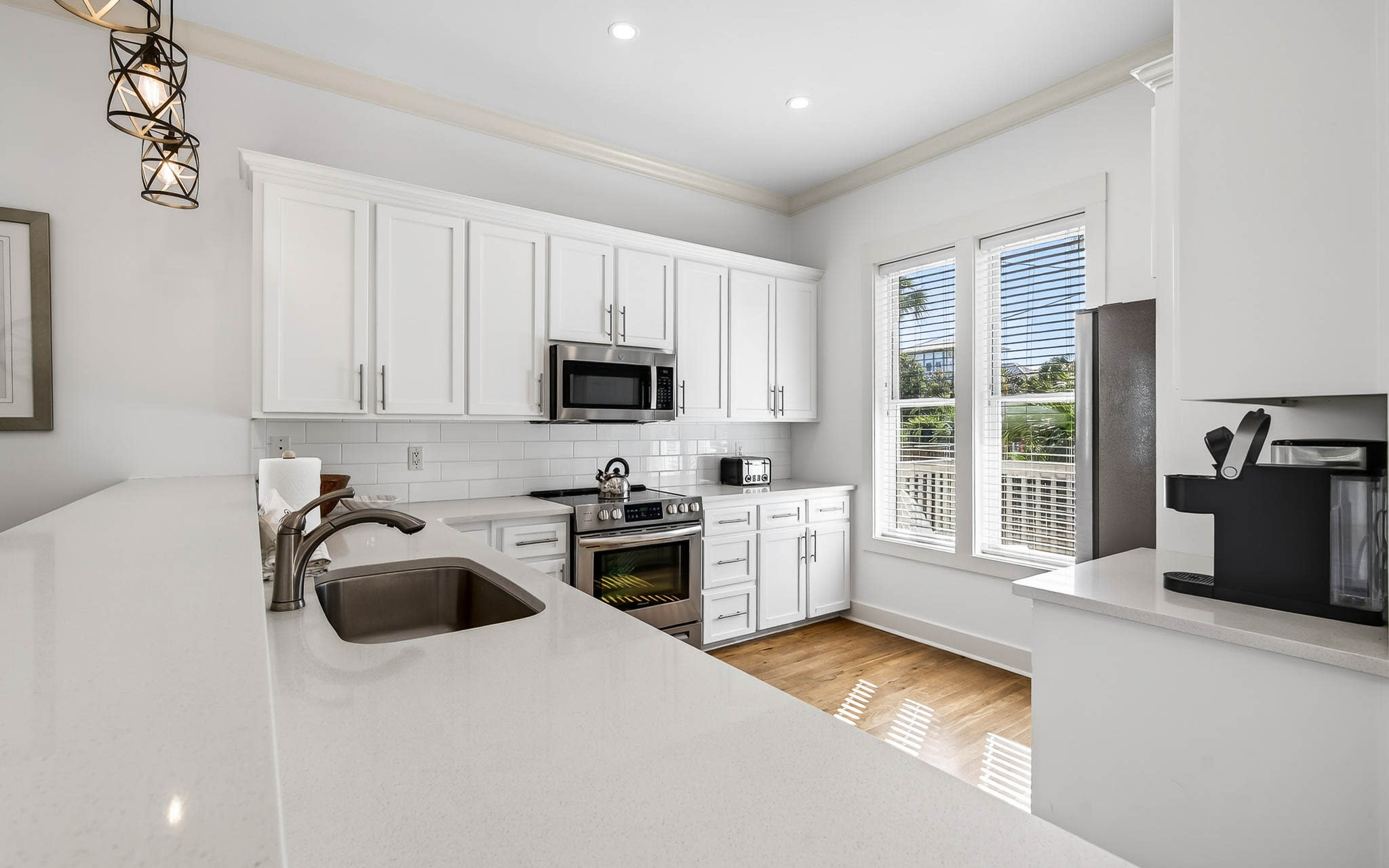 Your modern kitchen awaits with pristine white cabinets, quartz counters, and stainless appliances—perfect for preparing memorable meals during your stay.