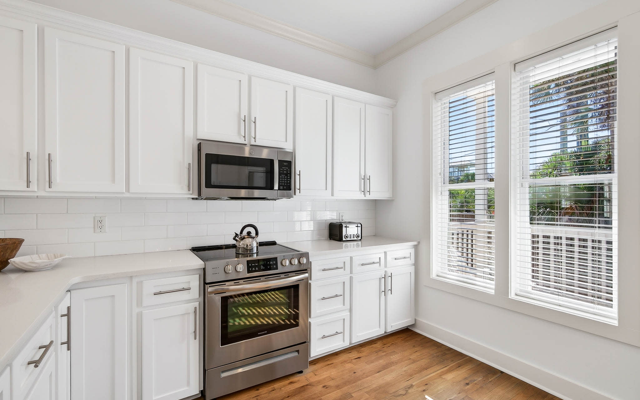 Your fully equipped kitchen features crisp white cabinets, stainless steel appliances, and warm hardwood floors, creating the perfect space for preparing home-cooked meals.