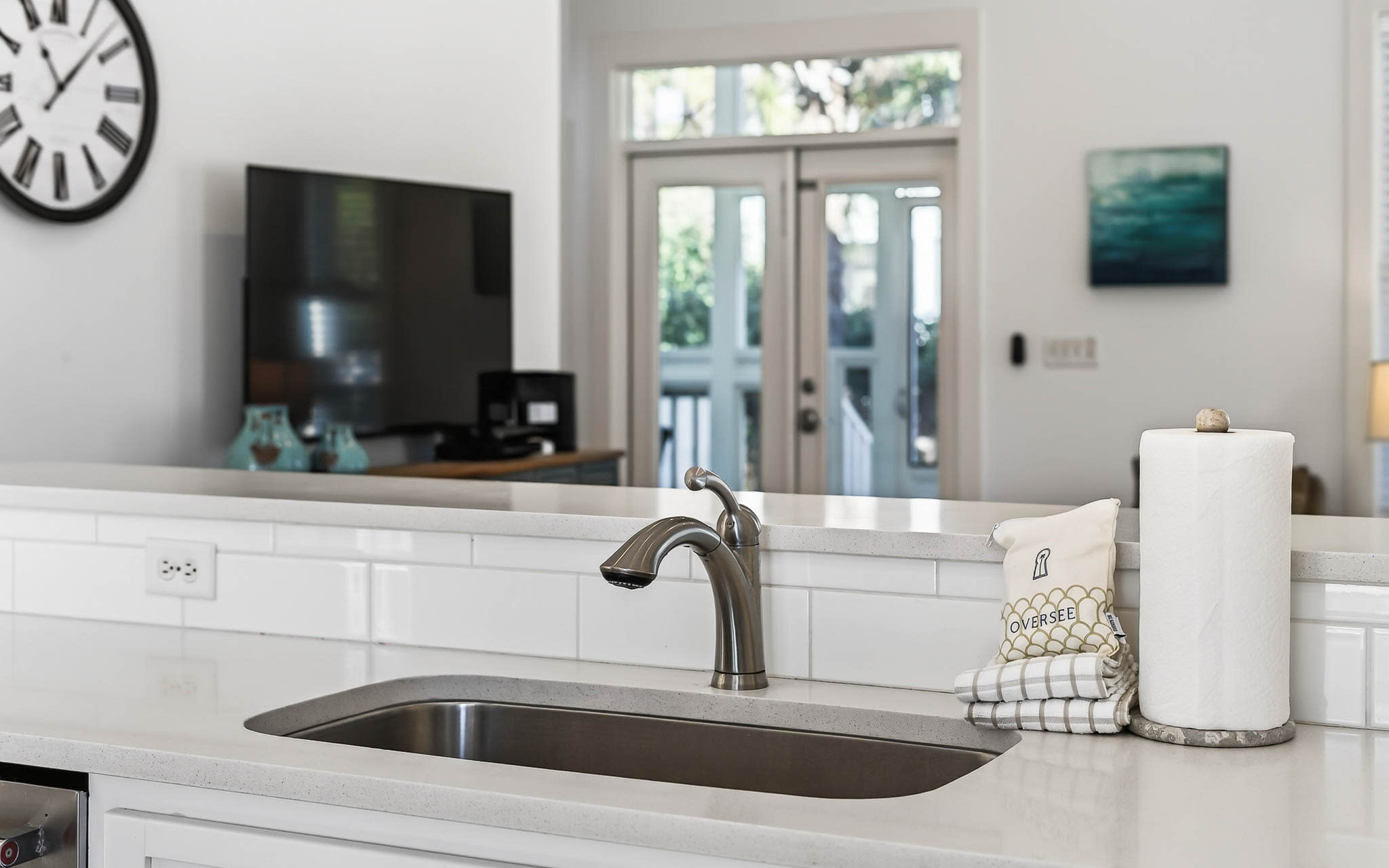 Your bright kitchen island invites cooking adventures with sleek quartz counters, undermount sink, and thoughtful touches like paper towels within easy reach.