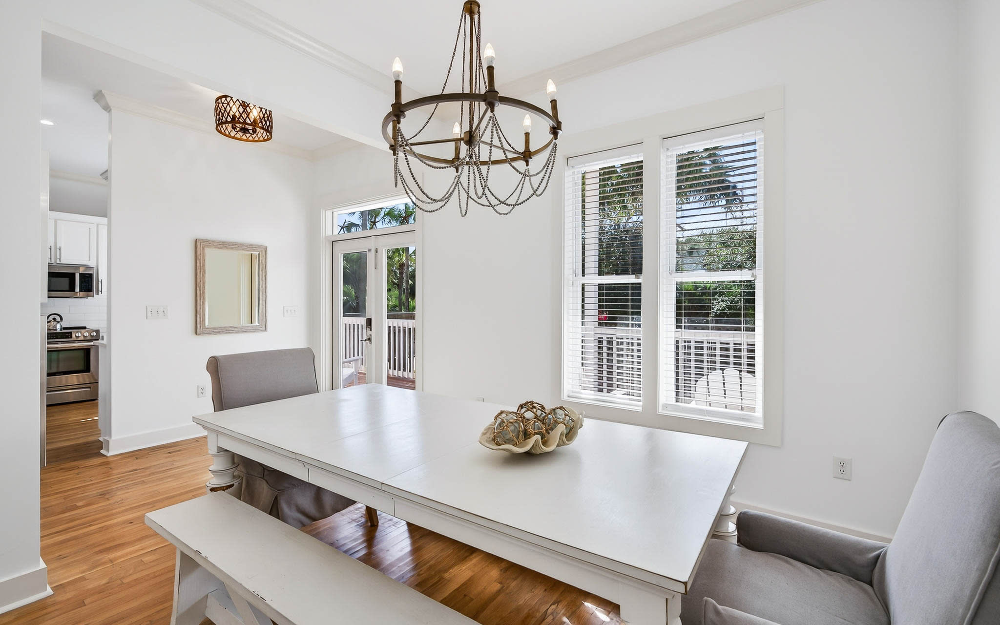 Gather around your elegant dining table where warm wood floors meet crisp white walls and natural light streams through French doors.