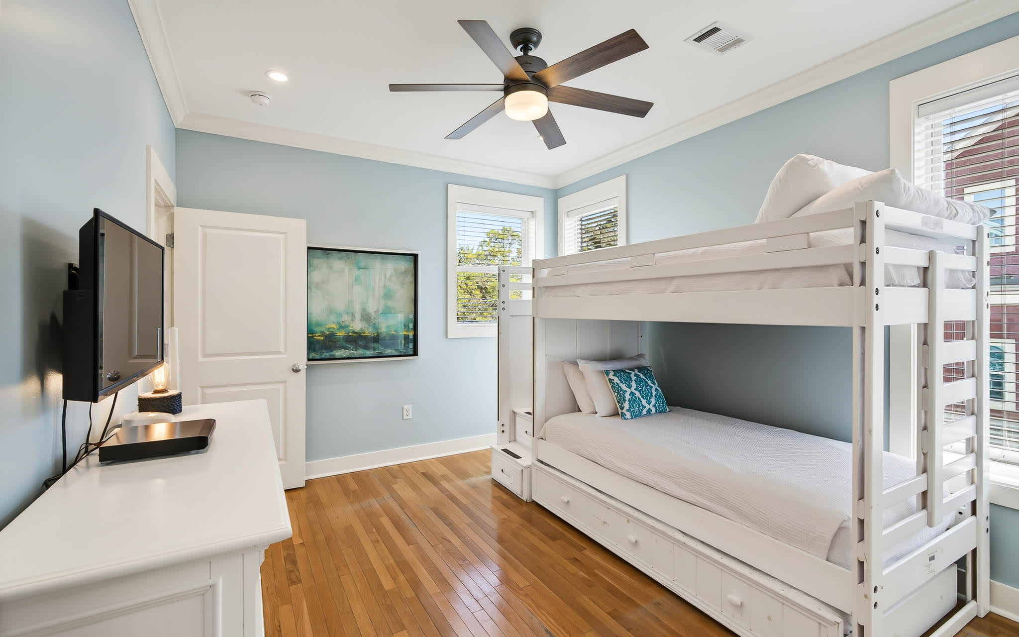 Your kids will love this bright bunk room with calming blue walls, ceiling fan, and TV for cozy bedtime stories.