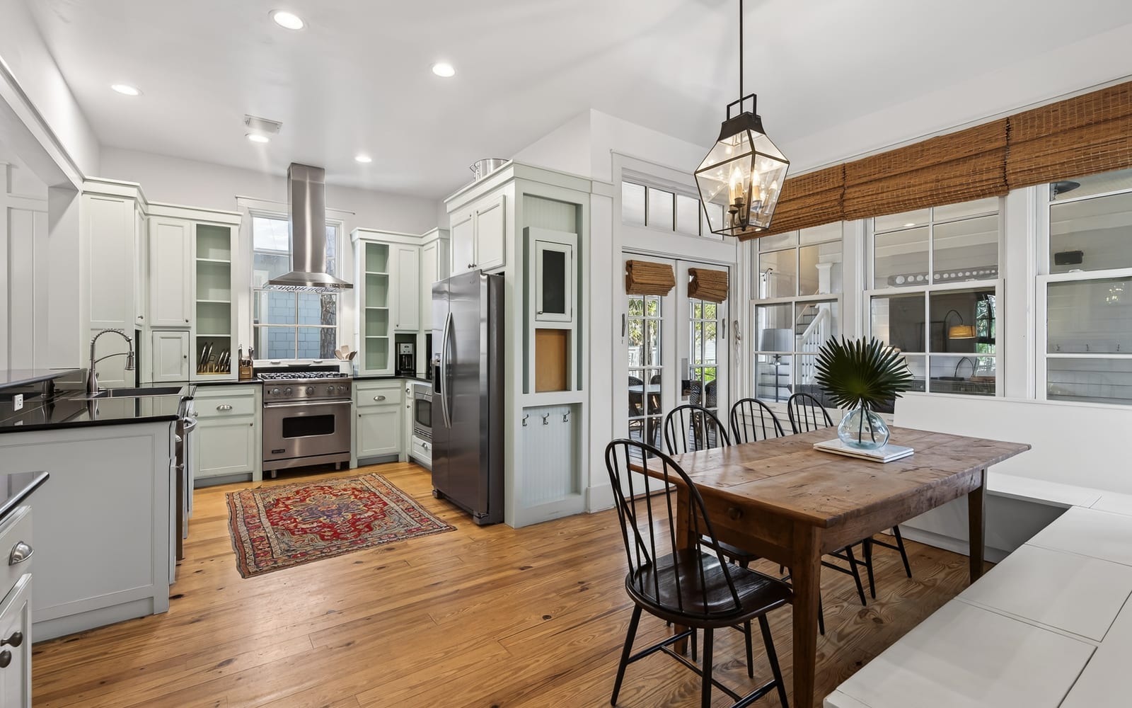 Gather around the rustic dining table in this bright, chef-inspired kitchen where warm wood floors and charming lantern lighting create the perfect atmosphere for your meals.