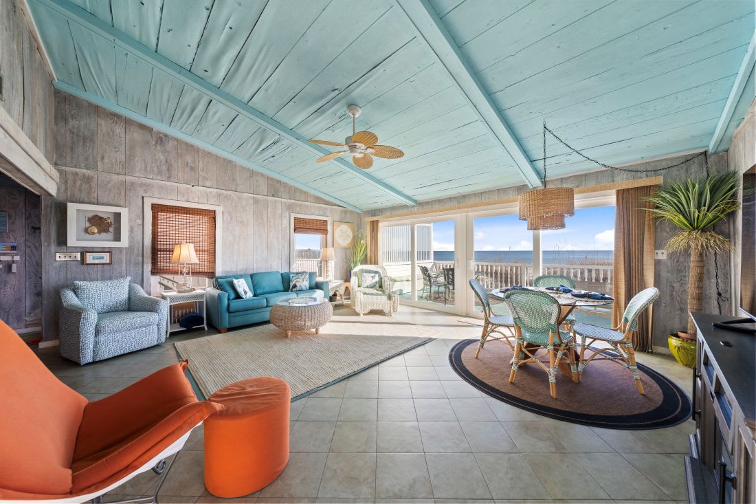 Relax in this stunning oceanfront living space where turquoise ceilings and vibrant furnishings create your perfect coastal retreat.