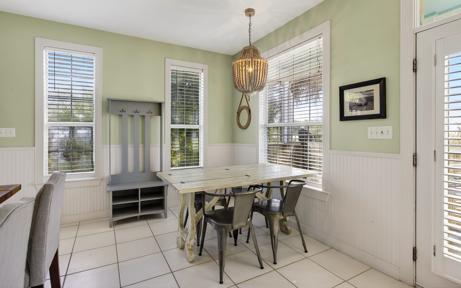 Gather around your bright dining nook with farmhouse charm, featuring a rustic table surrounded by windows that fill the space with natural light.