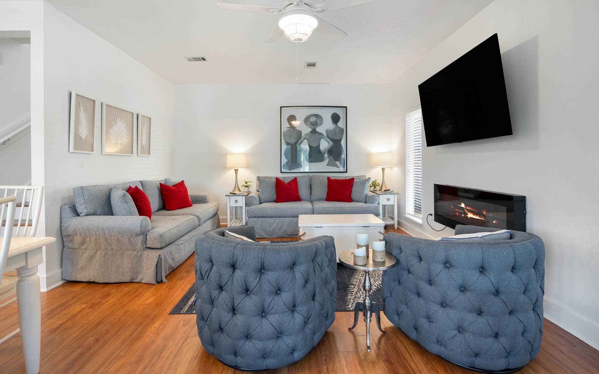 Sink into plush gray sofas with vibrant red pillows while the fireplace crackles nearby and your favorite show plays overhead.