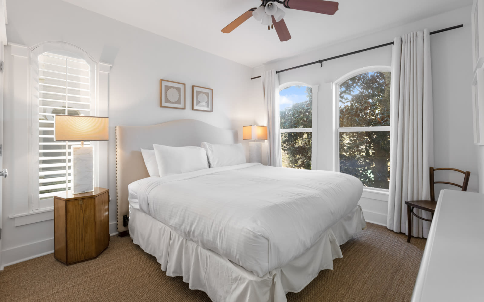 You'll love waking up in this serene bedroom with crisp white linens and warm natural light flooding through beautiful arched windows.