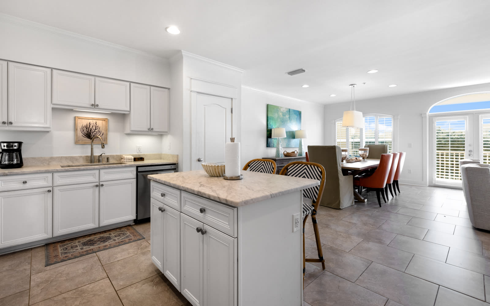 Your spacious kitchen flows seamlessly into the dining area, featuring elegant white cabinetry, modern appliances, and a convenient island for meal prep and casual dining.
