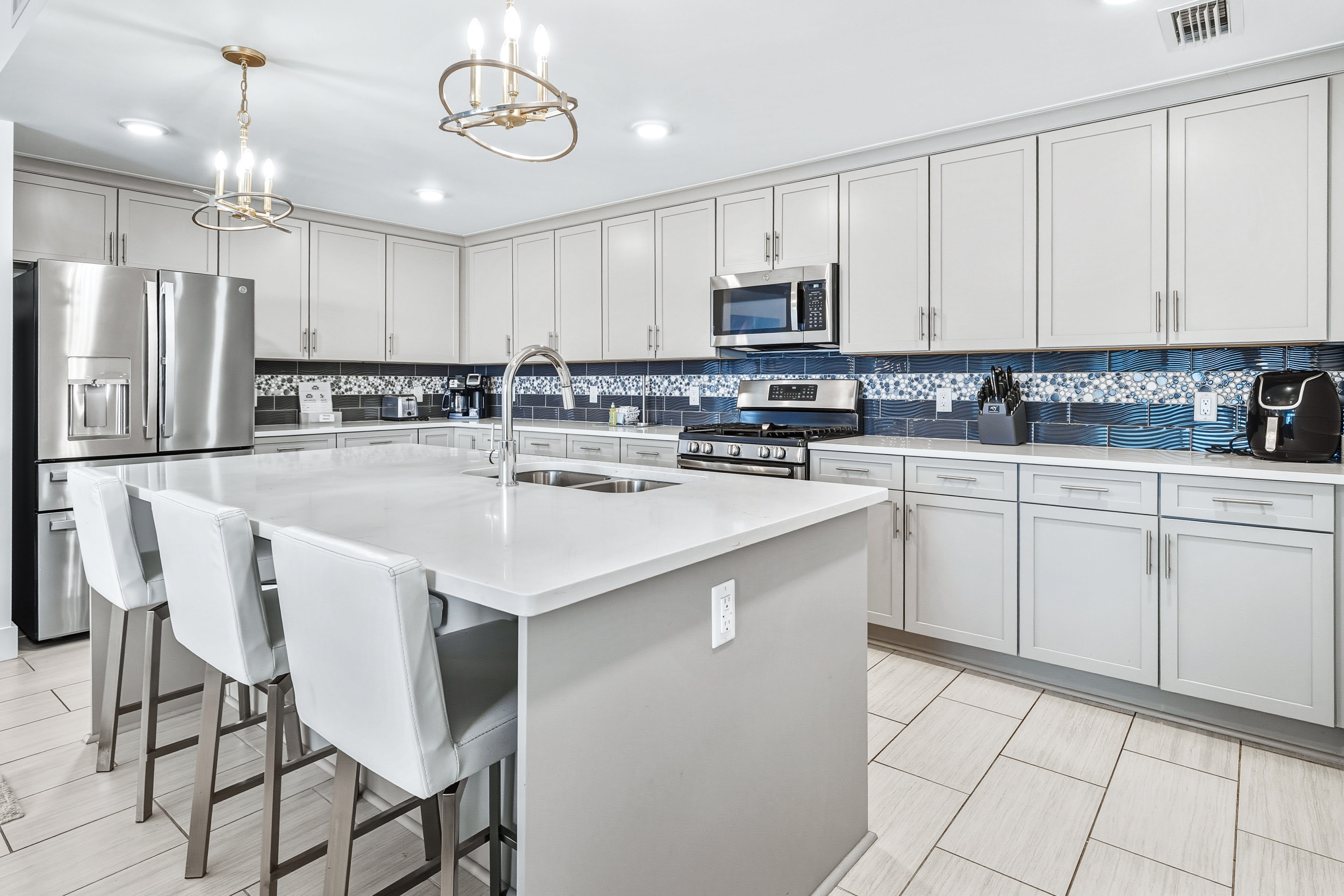 Your gourmet kitchen features sleek white cabinetry, granite countertops, and modern stainless appliances - perfect for preparing memorable meals during your stay.
