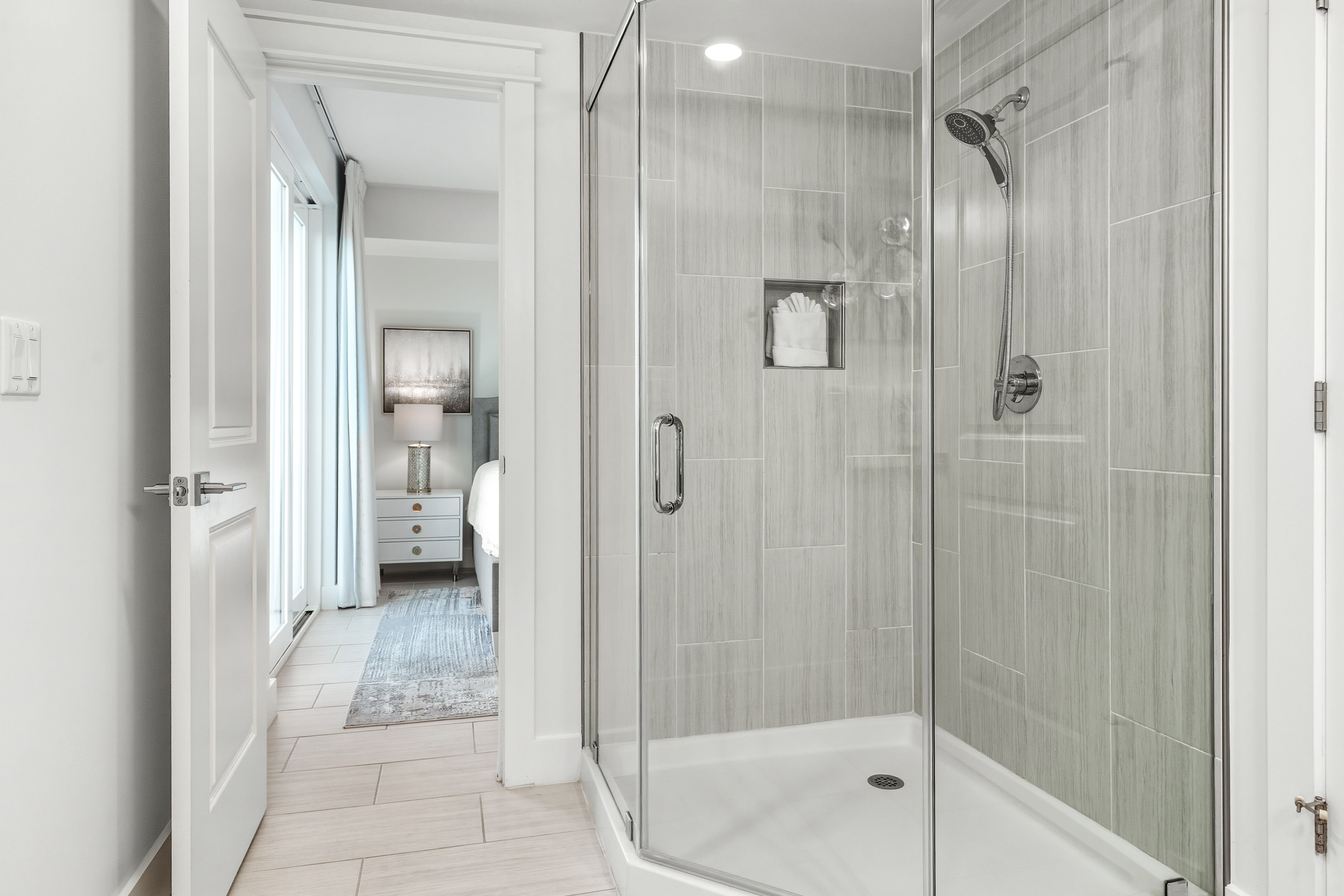 Step into your private spa-like shower with elegant glass doors and soothing gray tile that creates the perfect retreat after long days of exploring.