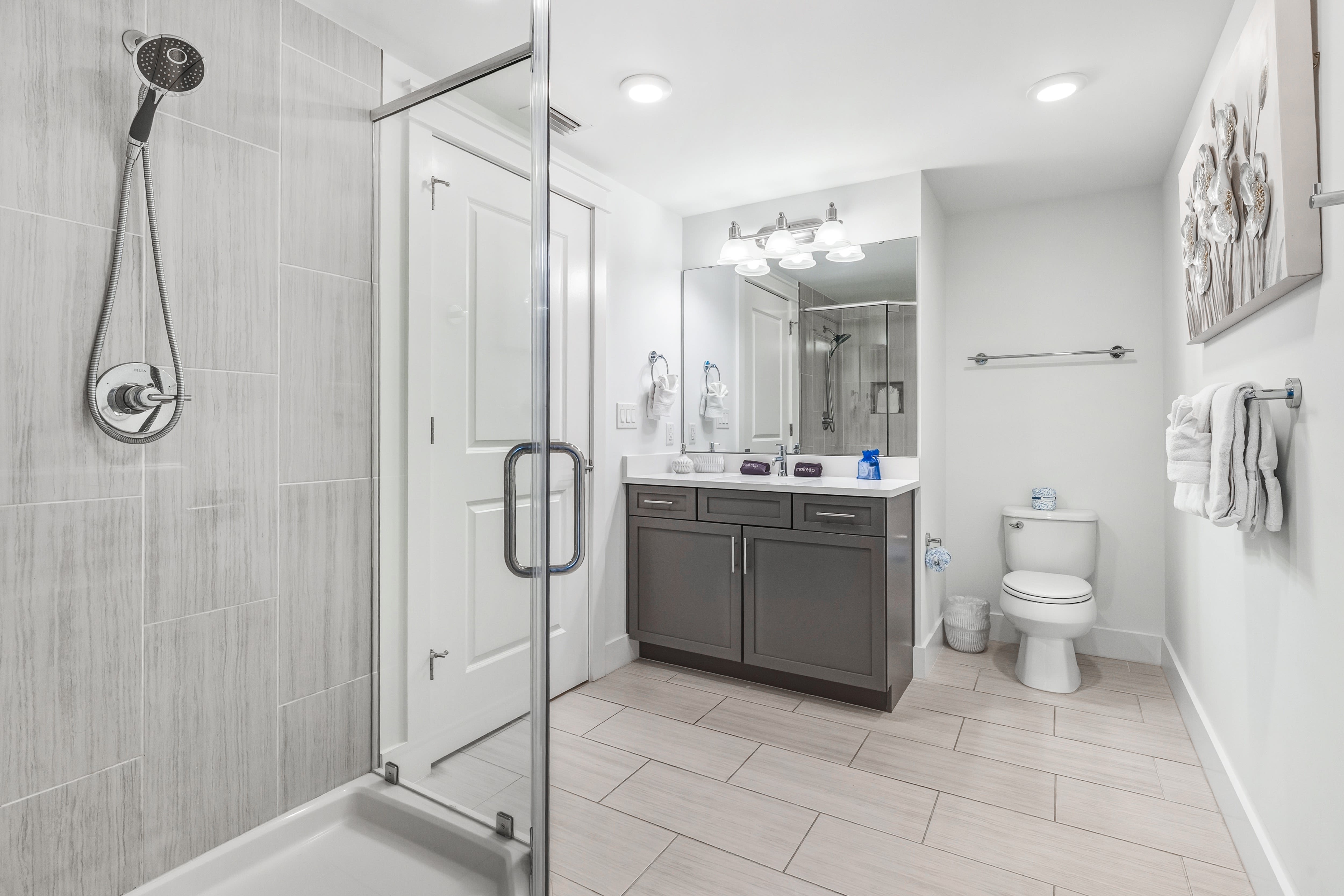 Step into your sleek modern bathroom with spacious glass-enclosed shower and ample vanity space for your morning routine.