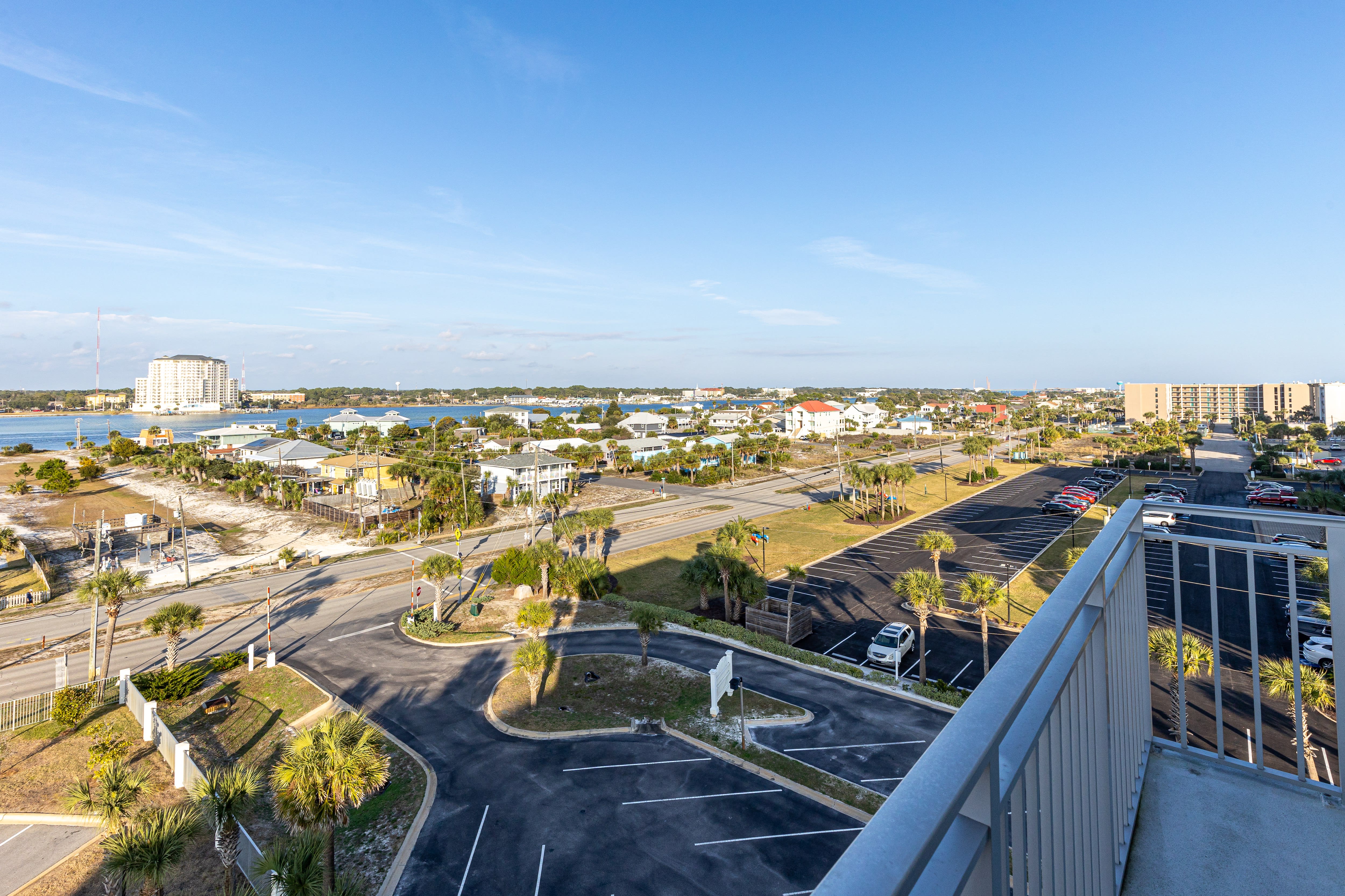 Aerial view of coastal area featuring waterfront buildings, palm-lined streets, and nearby bay waters.