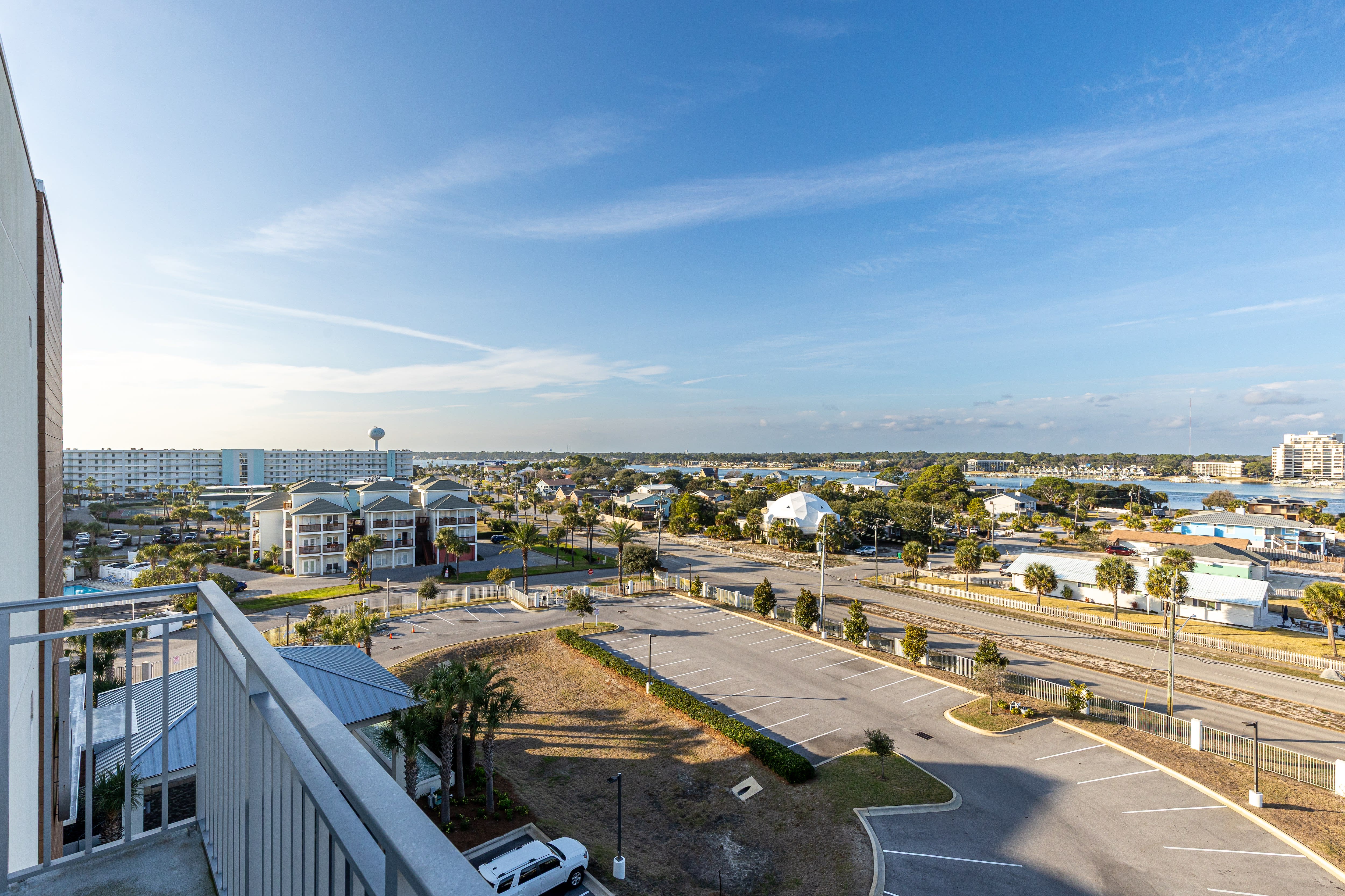 Elevated view showcasing the property's surroundings with coastal buildings, palm trees, and nearby amenities extending toward the horizon.