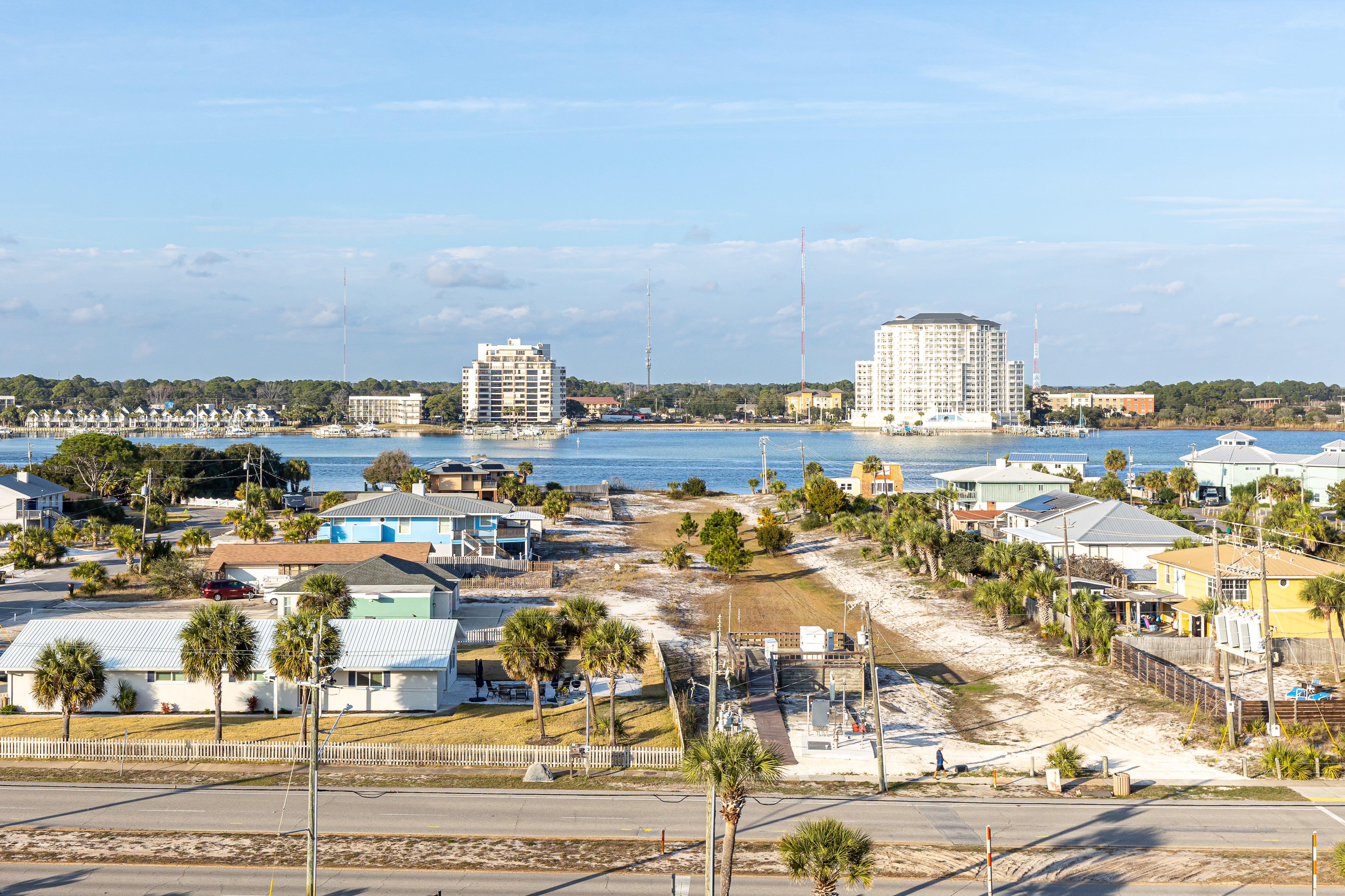 Coastal community featuring waterfront homes, high-rise buildings, and marina access across the bay.