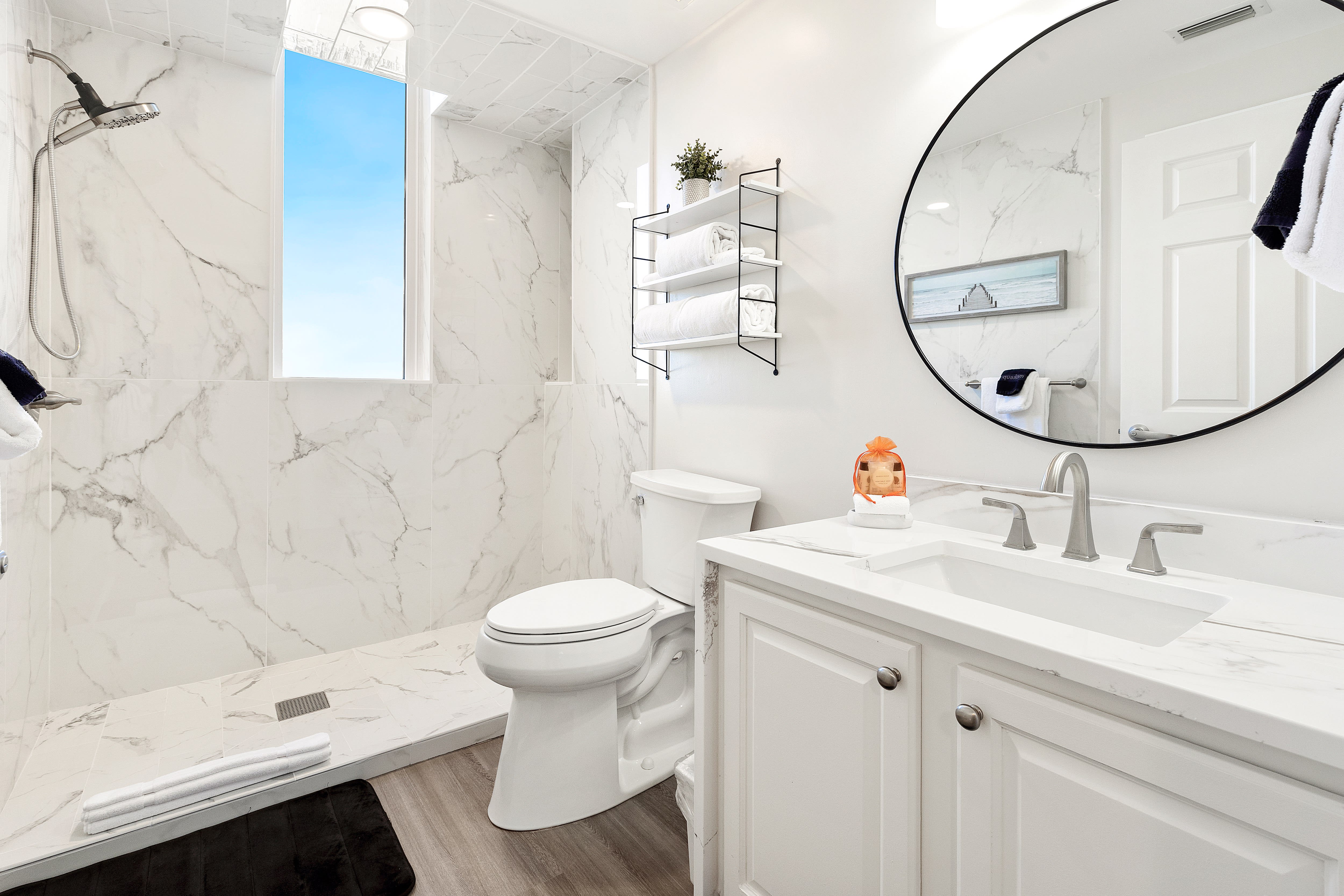 Step into your pristine marble sanctuary with luxurious rainfall shower, elegant vanity, and stunning natural light streaming through the window.