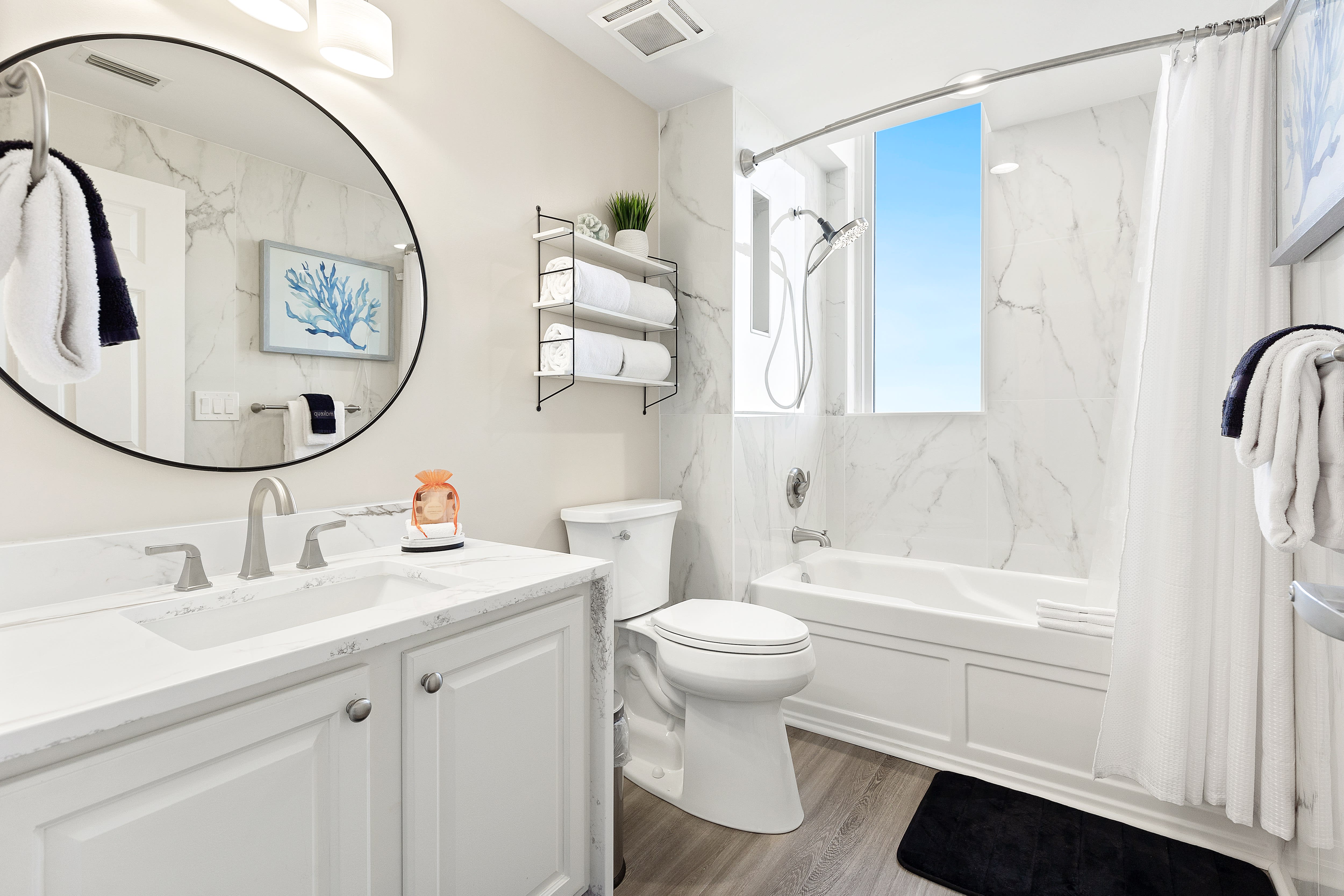 Unwind in your spa-like bathroom with marble details, rainfall shower, and coastal artwork creating your personal retreat.