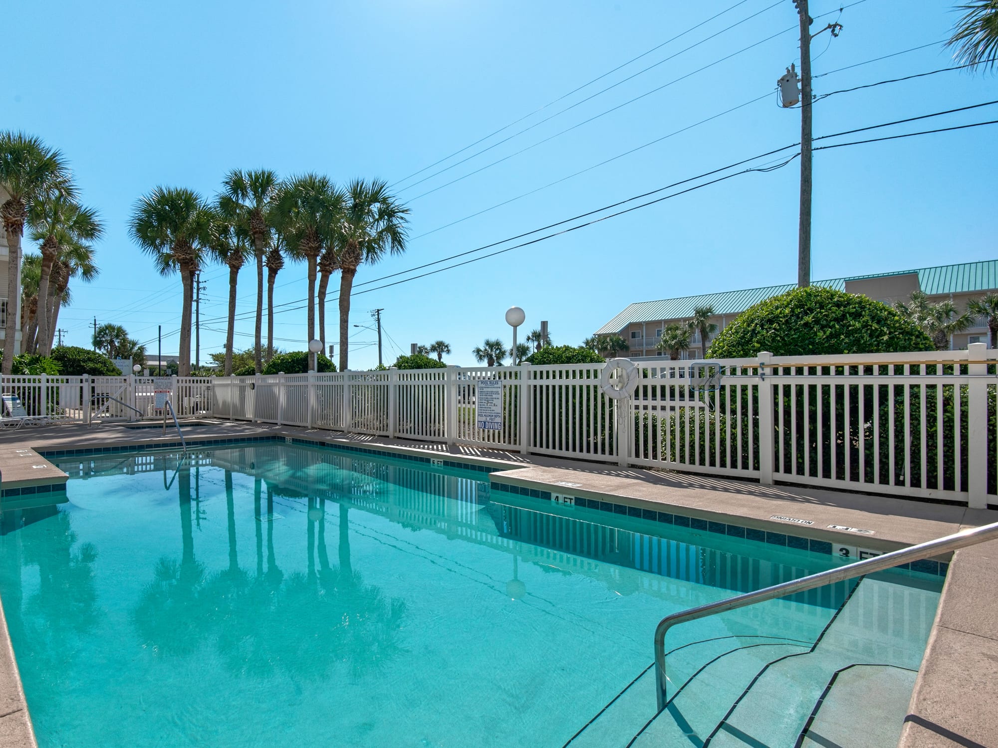 Crystal-clear pool surrounded by swaying palm trees offers your perfect tropical escape under sunny Florida skies.