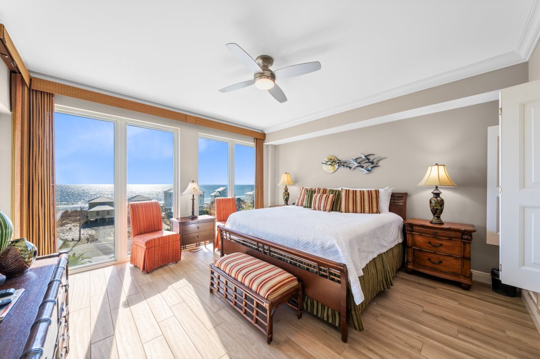 Your beachfront bedroom offers stunning sea views through floor-to-ceiling windows, with coastal breezes from the ceiling fan creating perfect relaxation.