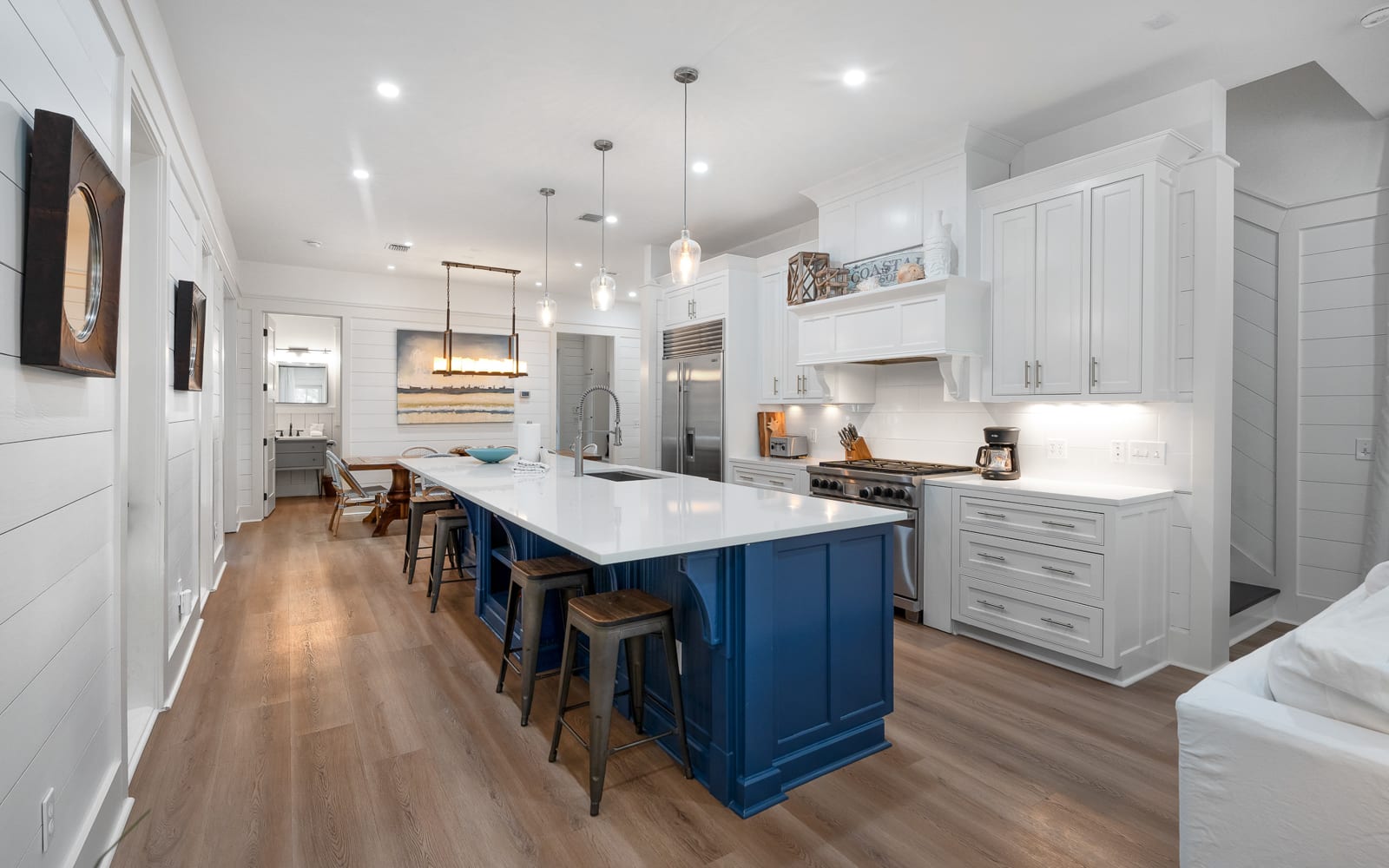 Your gourmet kitchen awaits with gleaming white countertops, a stunning navy island, and warm wood floors that invite barefoot mornings.