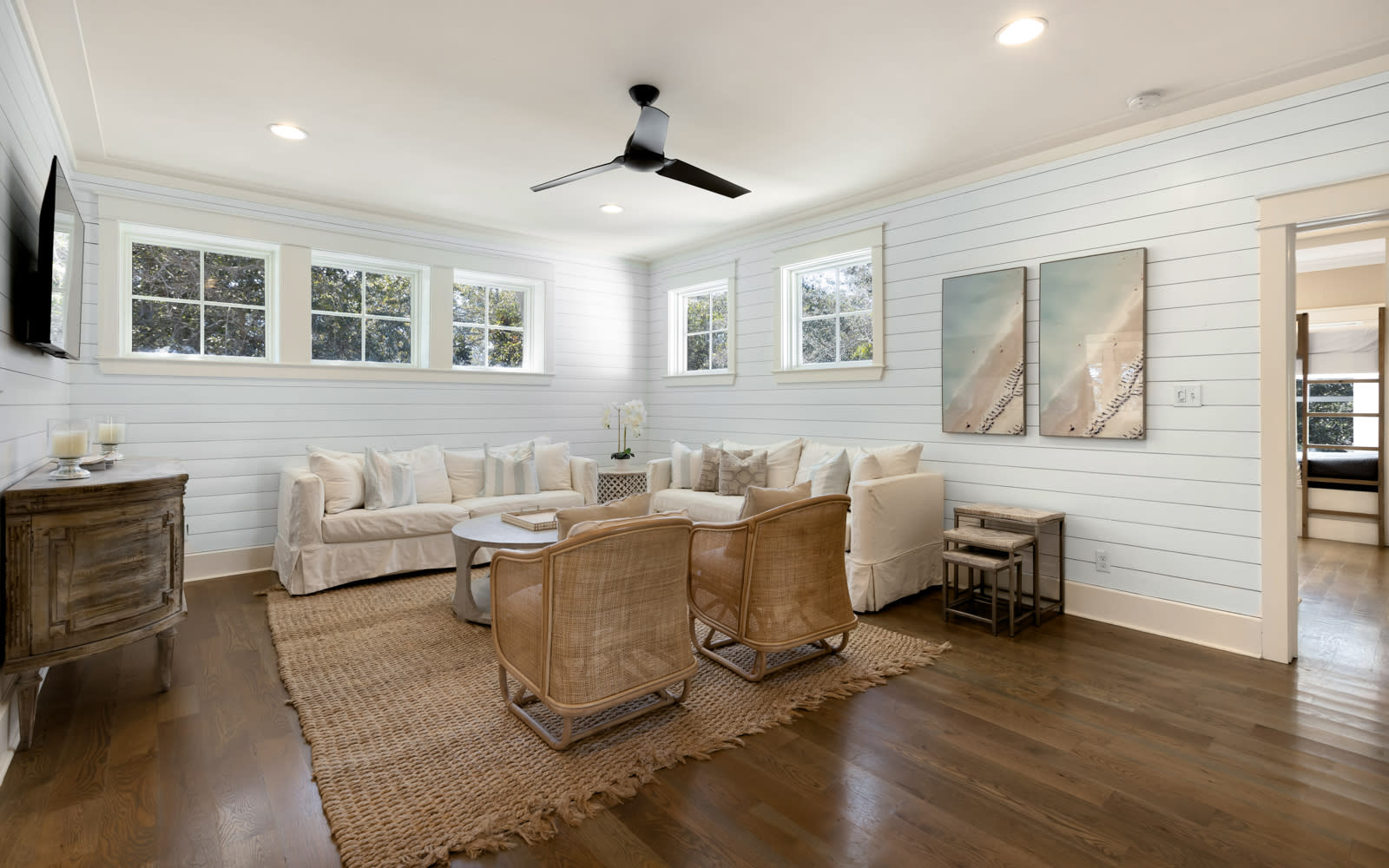 Unwind in your bright coastal-style living room with plush seating, warm wood floors, and charming shiplap walls that create the perfect retreat.