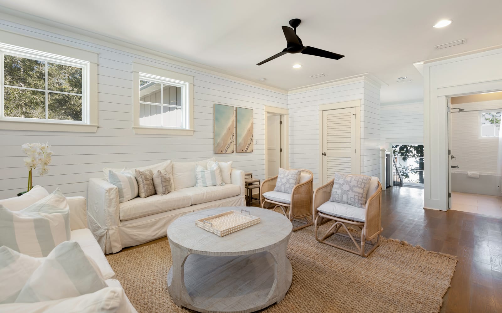 Unwind in your elegant living room featuring plush white seating, warm wood accents, and coastal charm perfect for peaceful evening conversations.