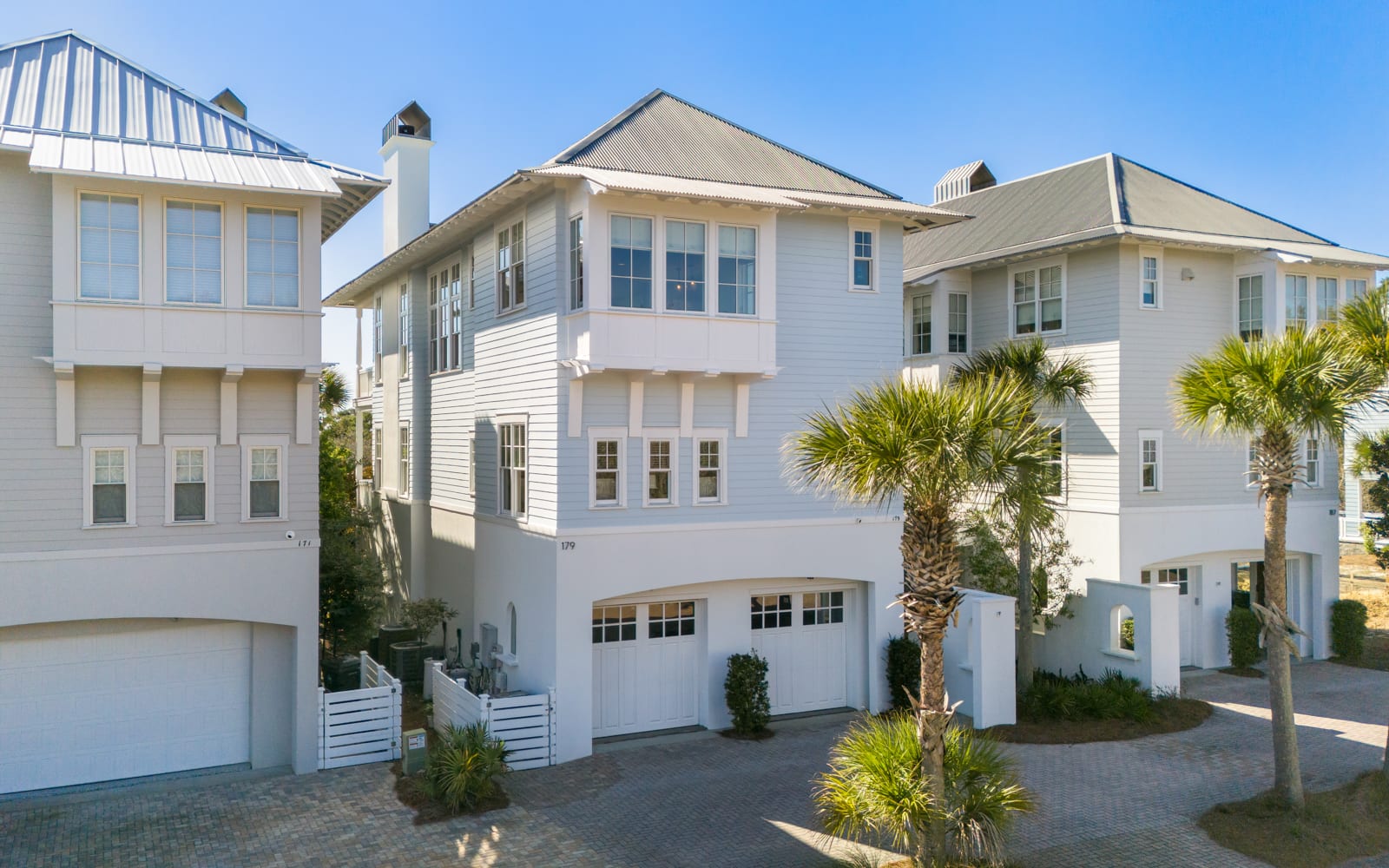 Beautiful coastal architecture showcases modern beach house design with palm-lined streets in an upscale neighborhood setting.