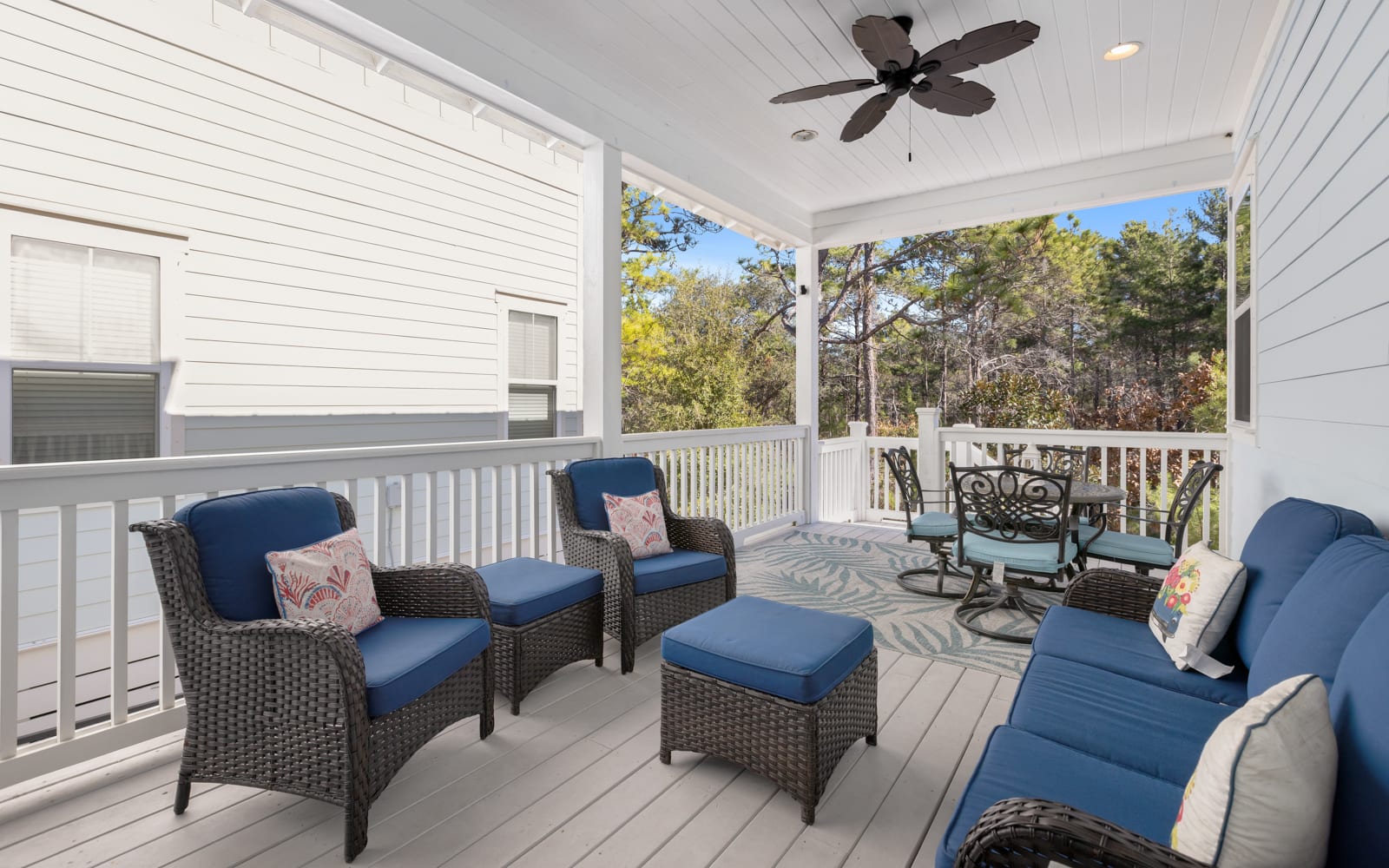 Unwind on your private covered porch with comfortable seating and ceiling fan, overlooking peaceful wooded surroundings.