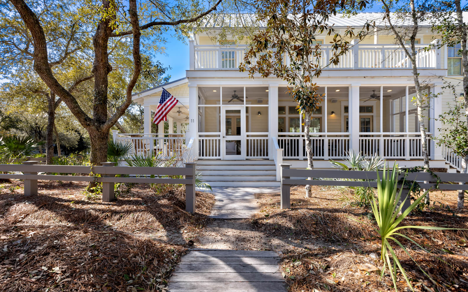 Charming coastal cottage with wraparound porch and mature oak trees creates the perfect retreat setting.