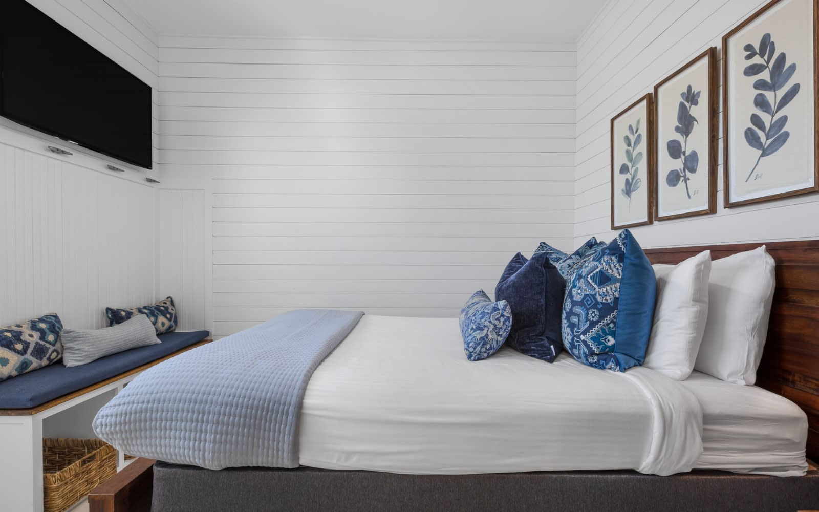 Sink into crisp white linens and plush blue pillows in your serene bedroom retreat, complete with coastal artwork and modern amenities.