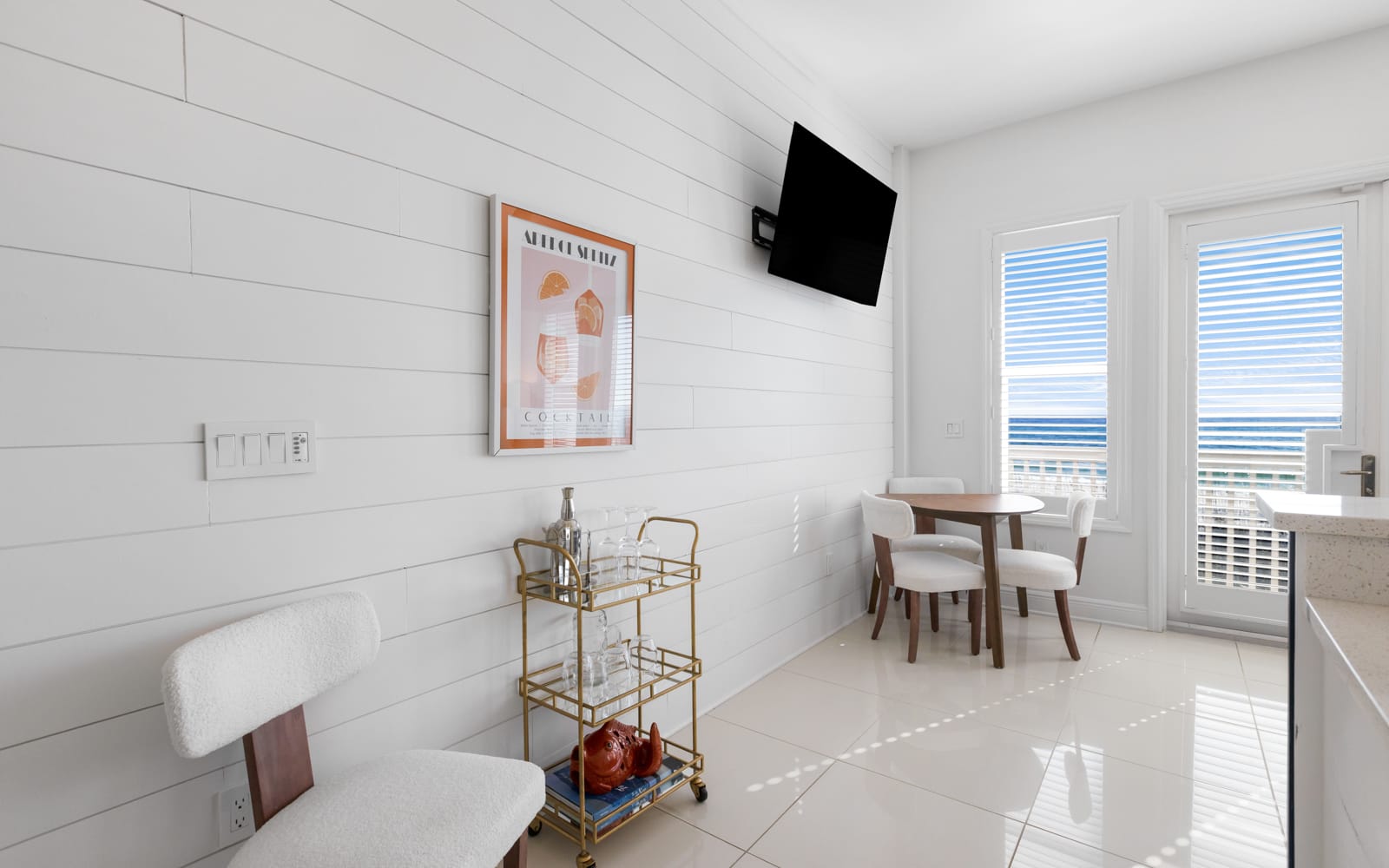 Your bright, modern dining space features clean white shiplap walls and a stylish round table where you'll enjoy meals with natural light streaming through large windows.