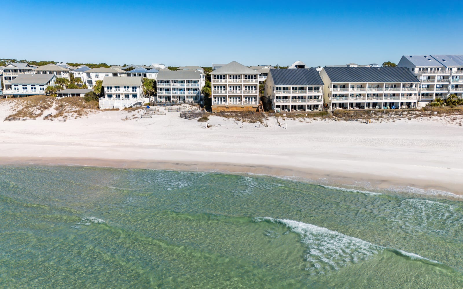 Beachfront property complex with direct access to pristine white sand and crystal-clear emerald waters.